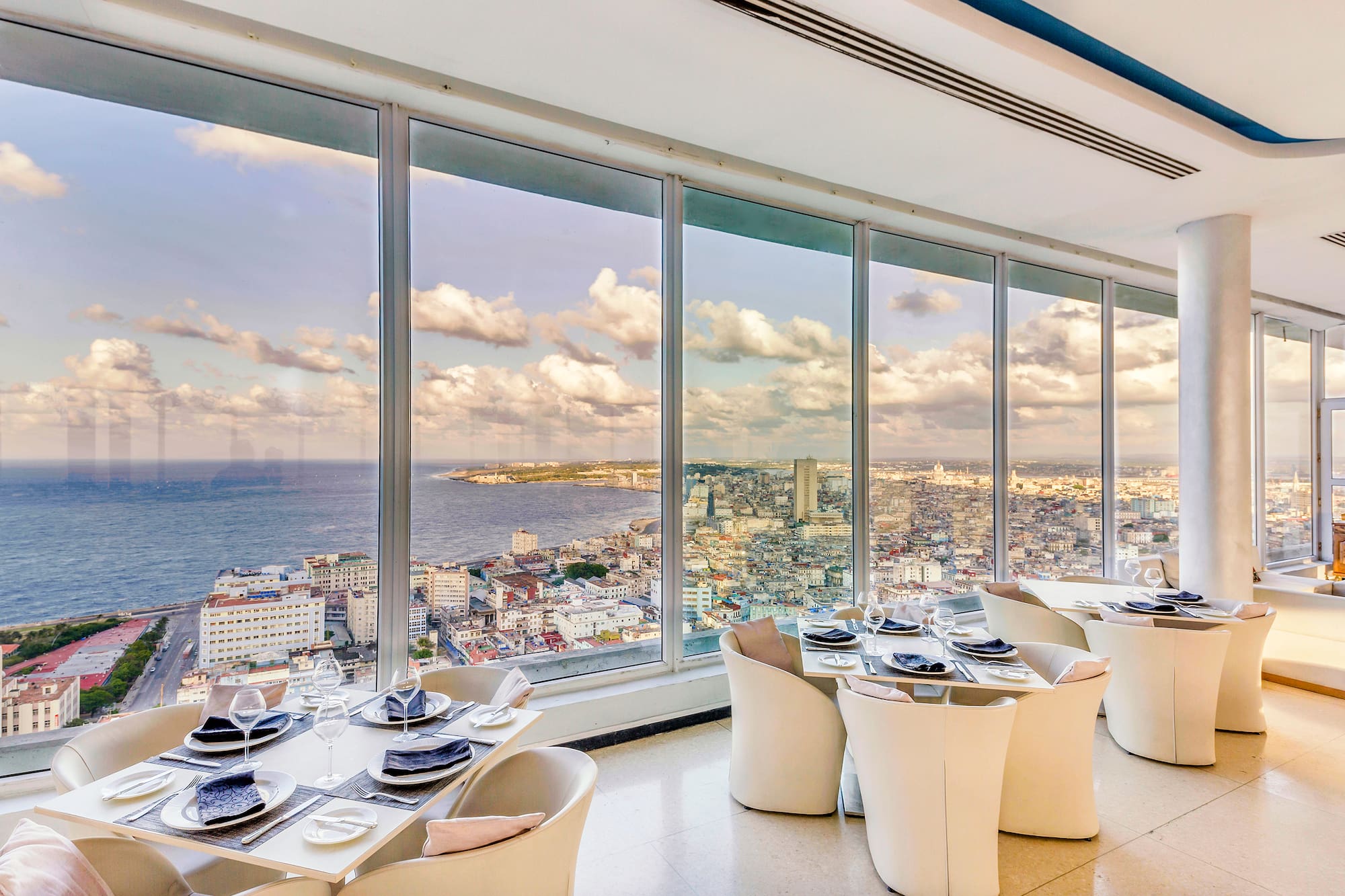 a room with large windows and tables and chairs