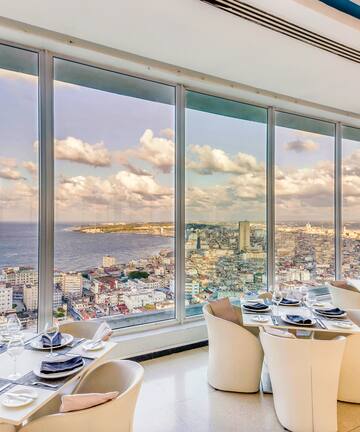 a room with large windows and tables and chairs
