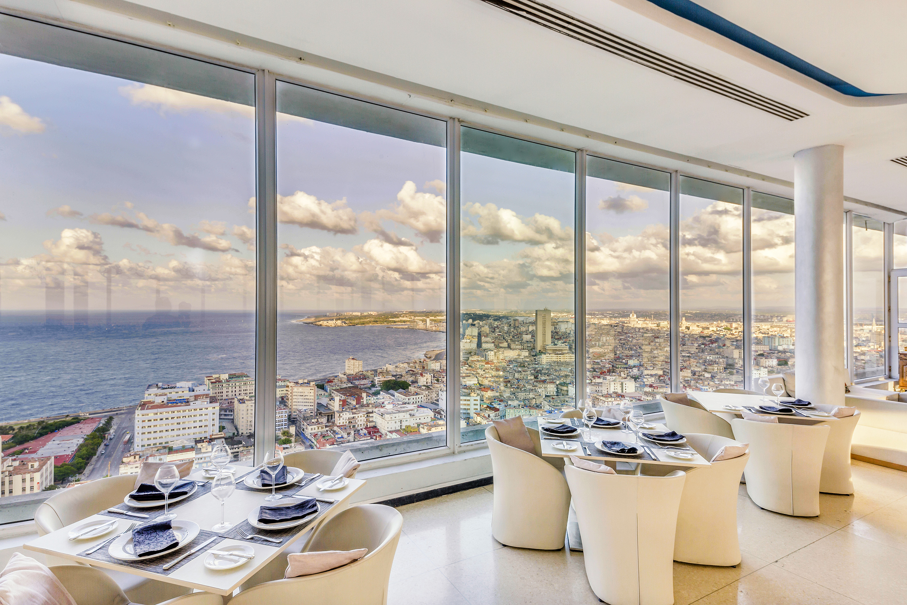 a room with large windows and tables and chairs