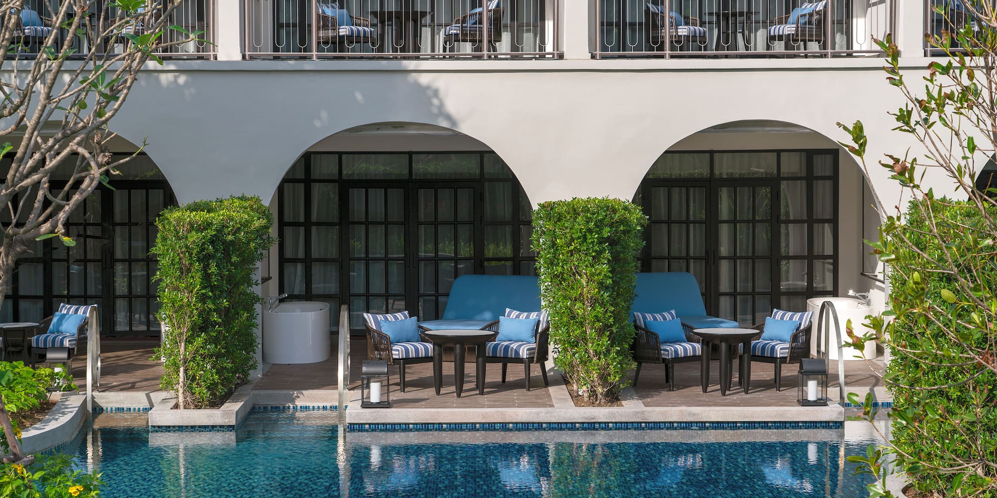 a pool with chairs and tables in front of a building