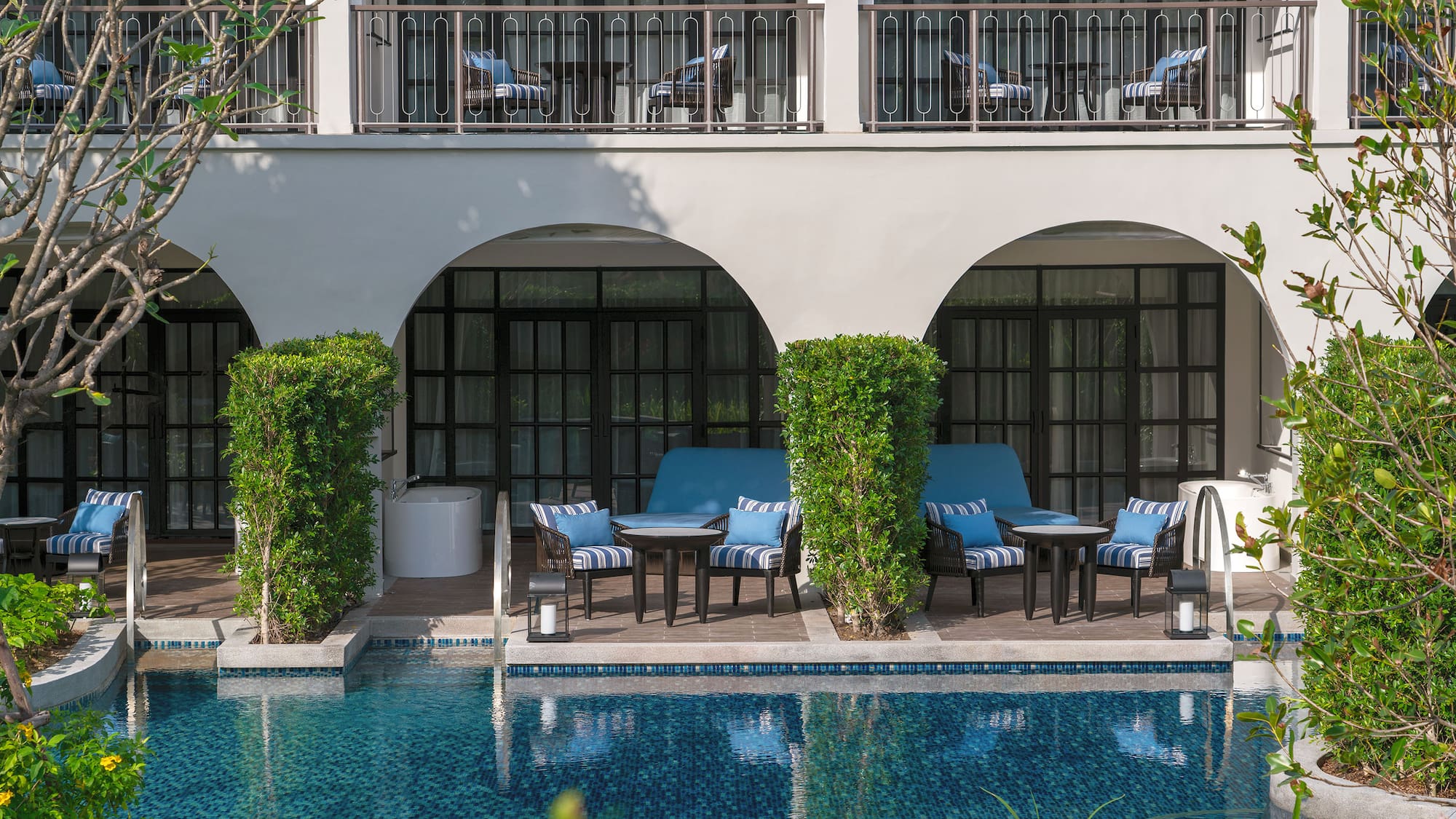 a pool with chairs and tables in front of a building