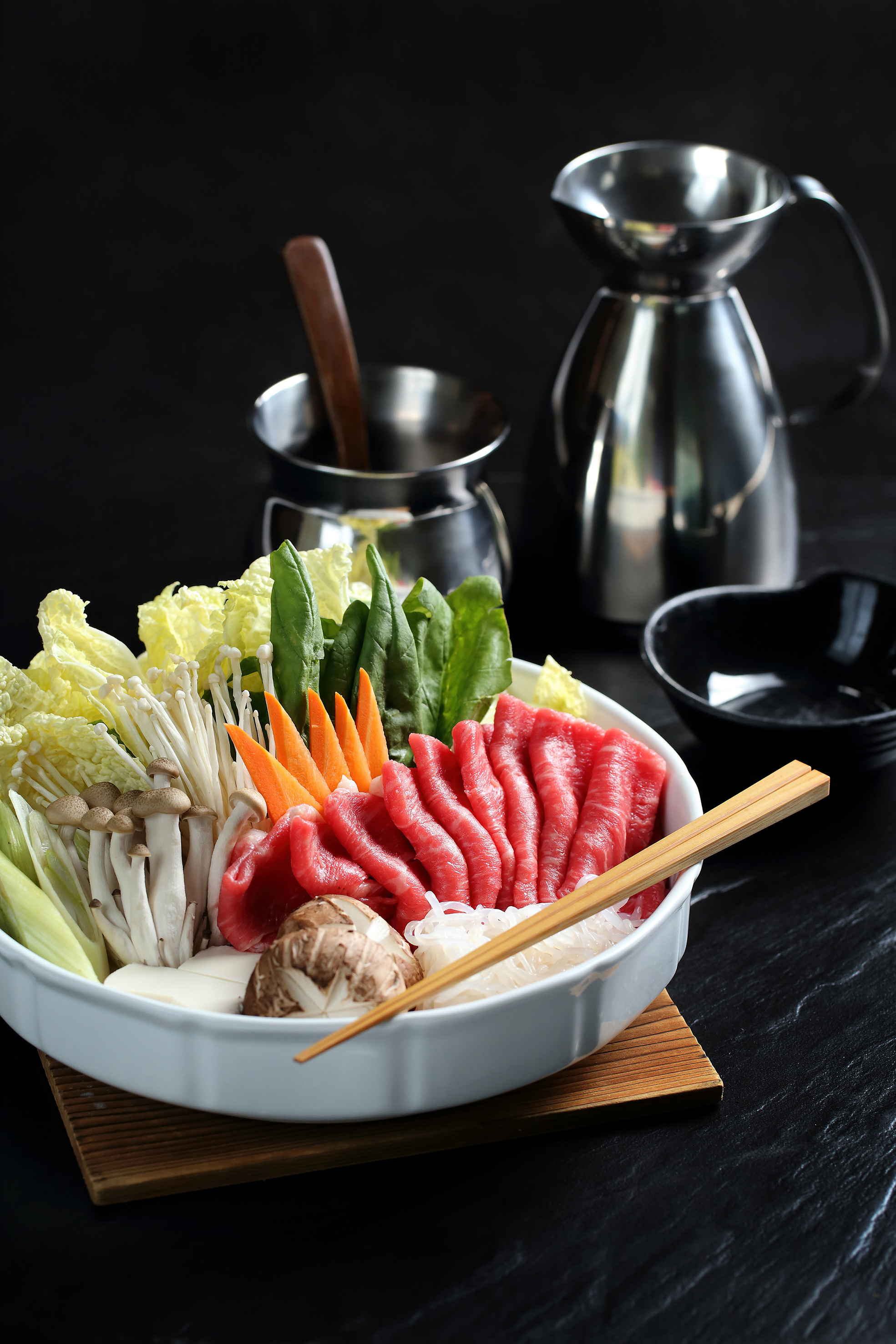 Raw beef, mushrooms, and fresh vegetables for shabu-shabu hot pot.