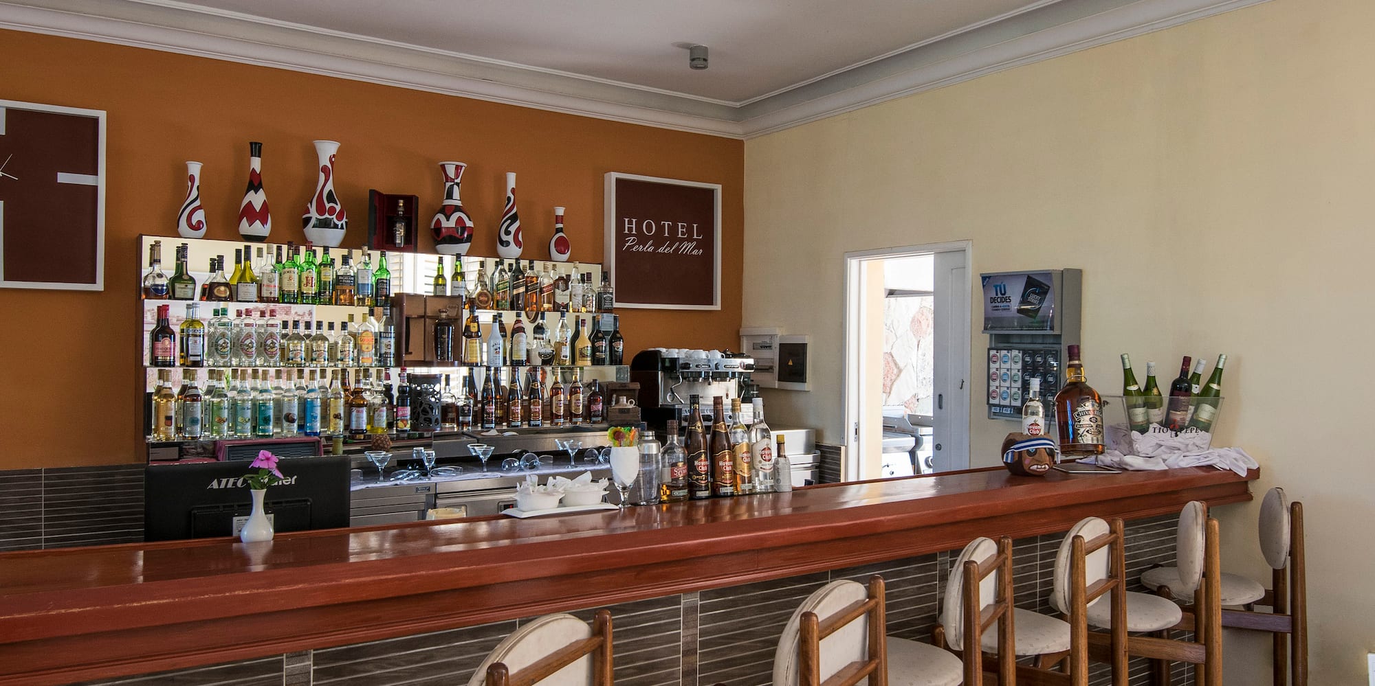 a bar with chairs and bottles on the wall