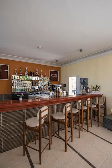 a bar with chairs and bottles on the wall
