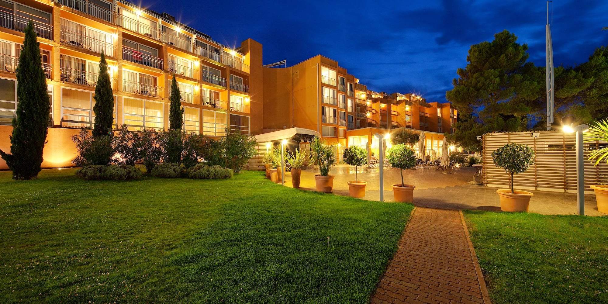 a building with lights on and a lawn