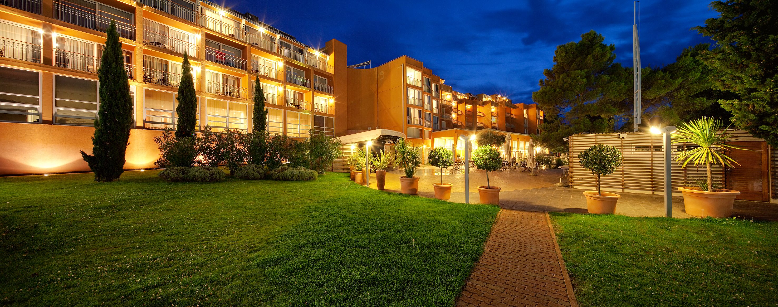 a building with lights on and a lawn