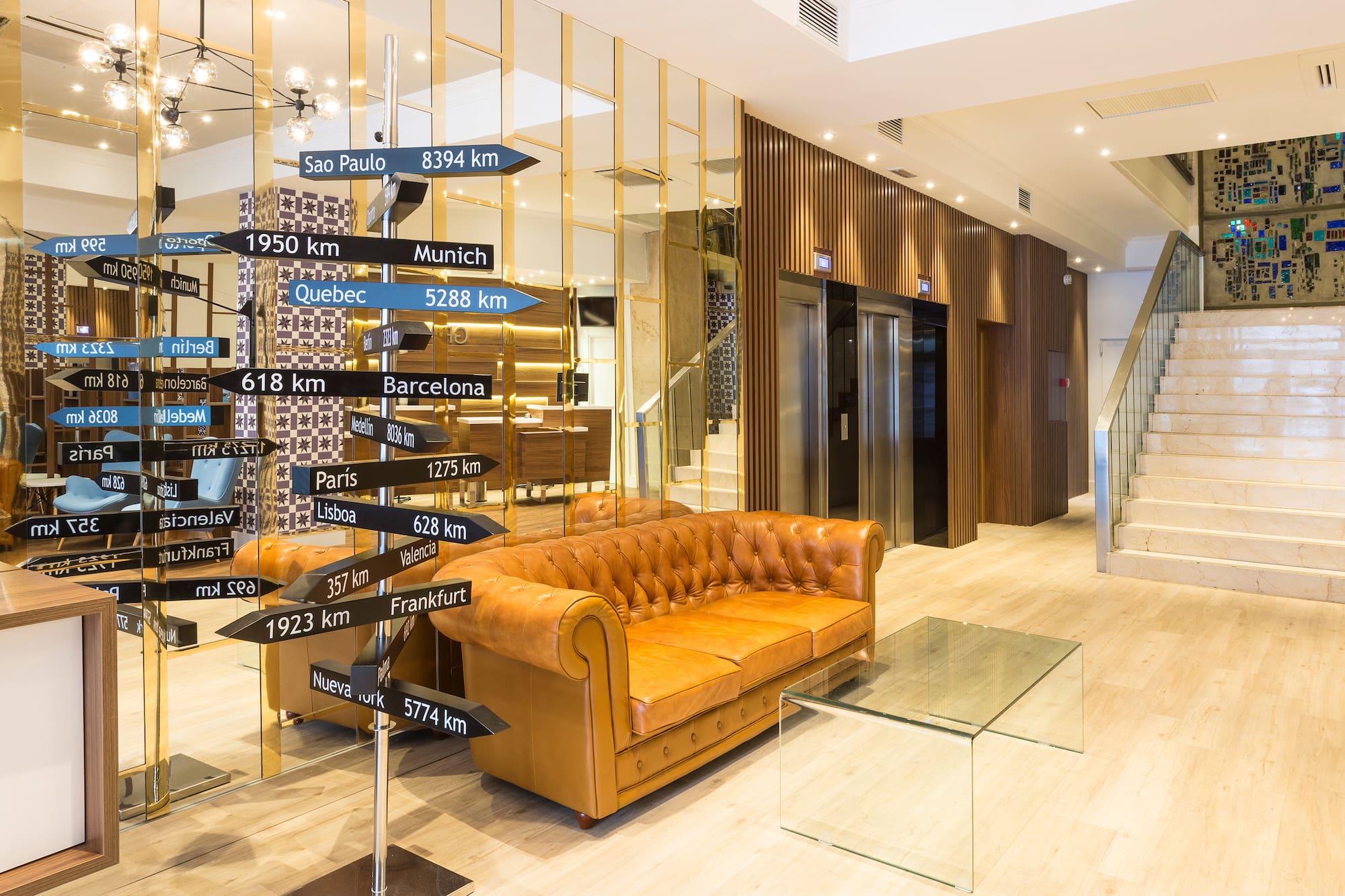 Hotel lobby with travel destination signpost and brown leather sofa.