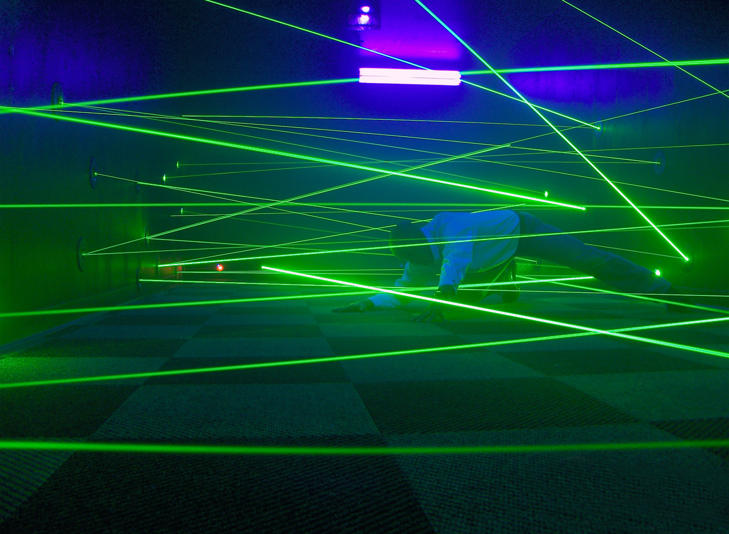 Person navigates a challenging green laser maze on a checkered floor.