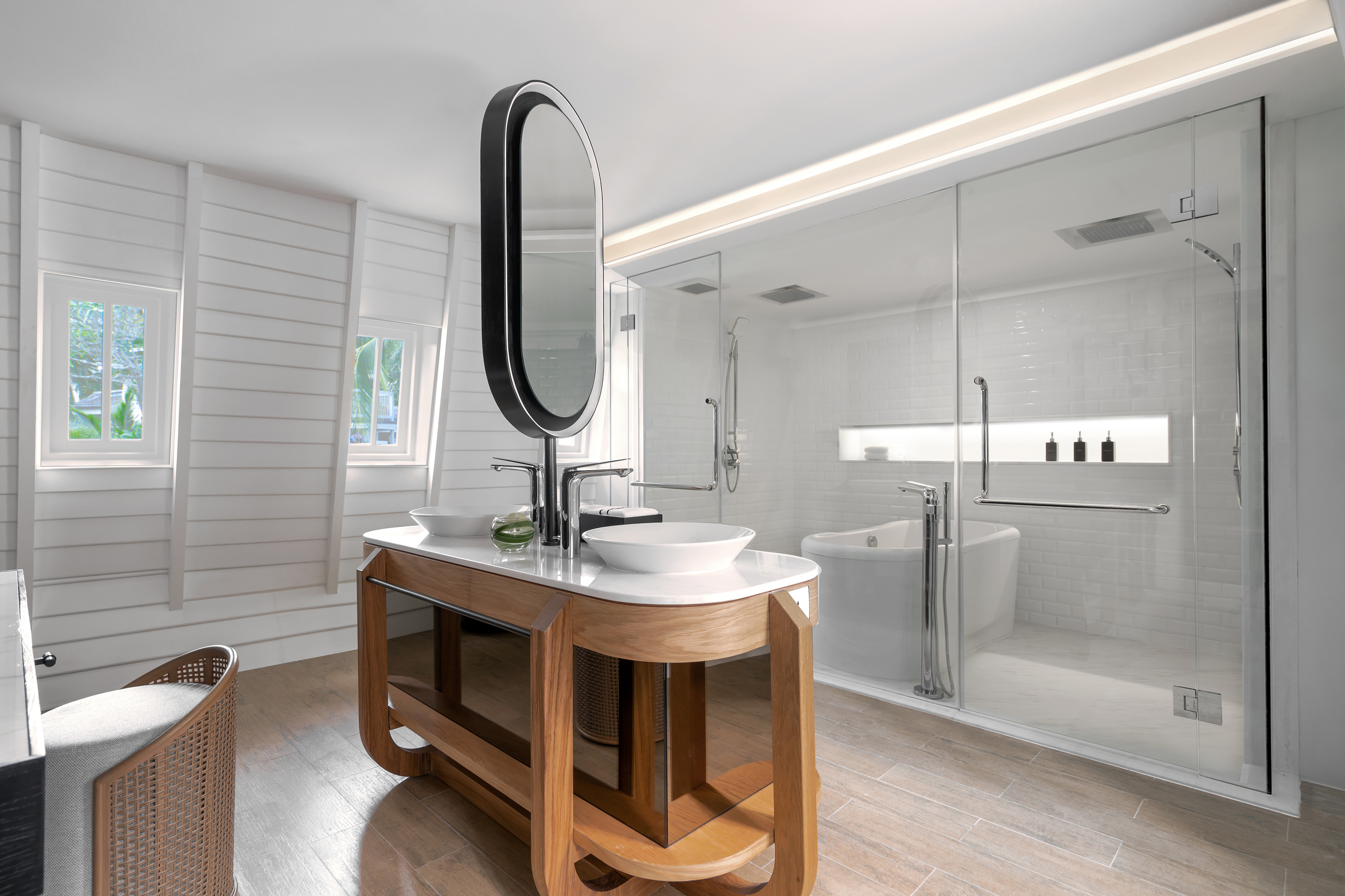 Contemporary bathroom with wood double vanity, oval mirror, glass shower, tub.