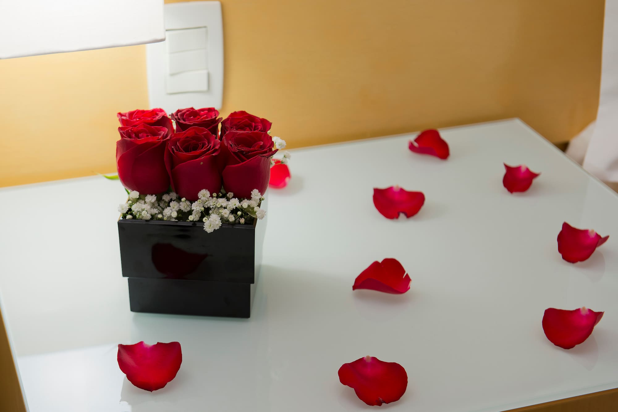 a bouquet of red roses in a black square box on a white surface