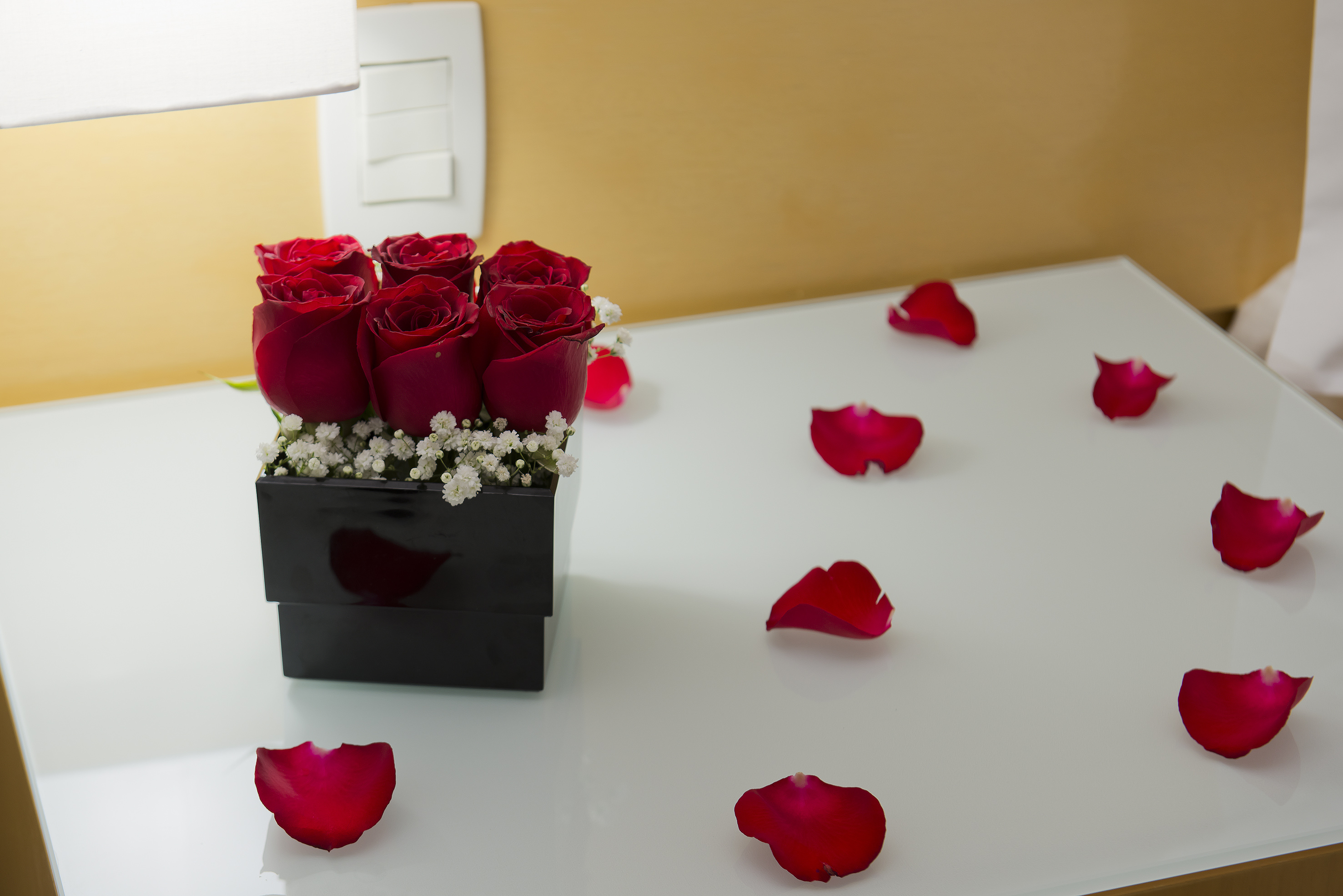 a bouquet of red roses in a black square box on a white surface