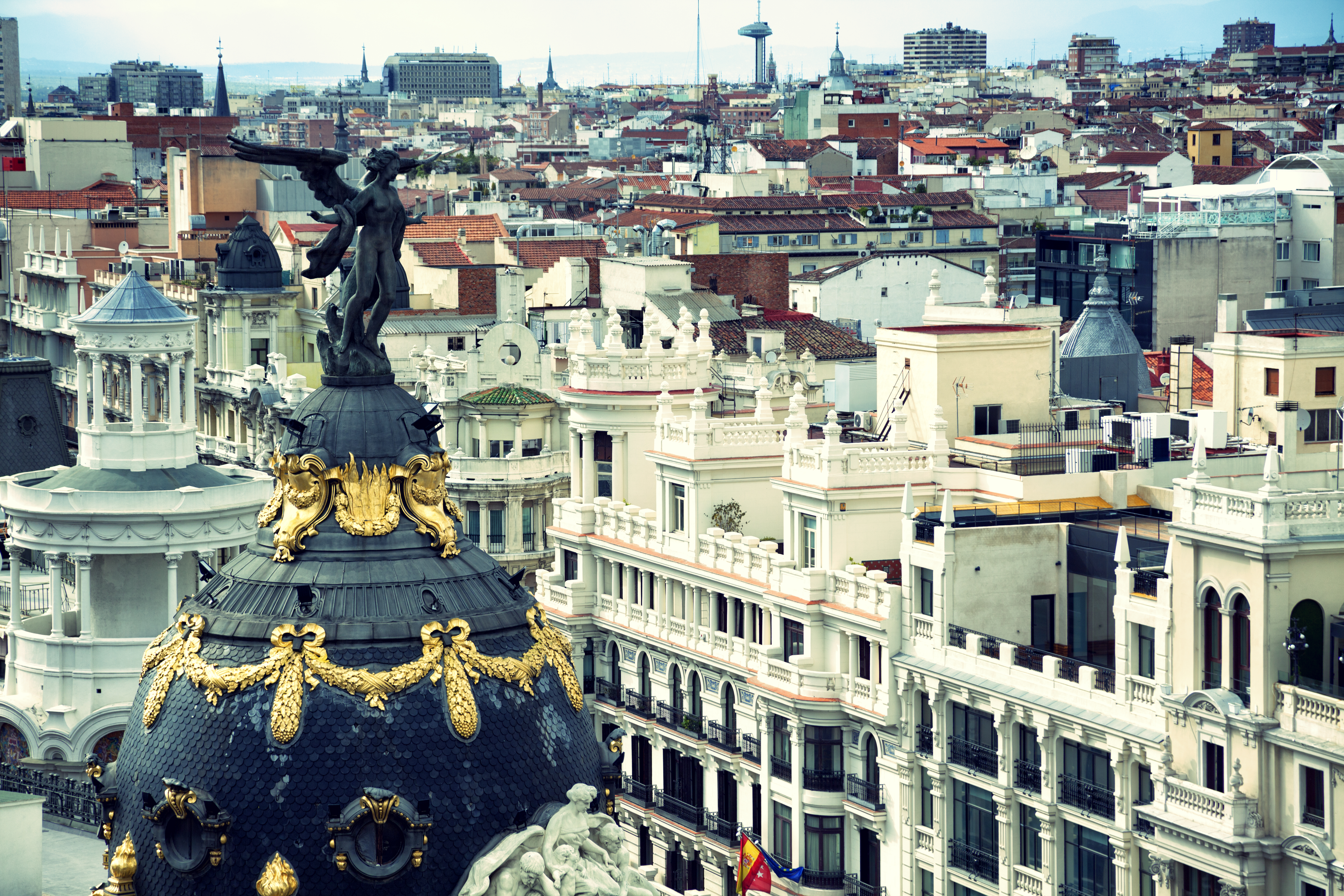 Iconic winged statue atop Metrópolis Building, panoramic Madrid cityscape.