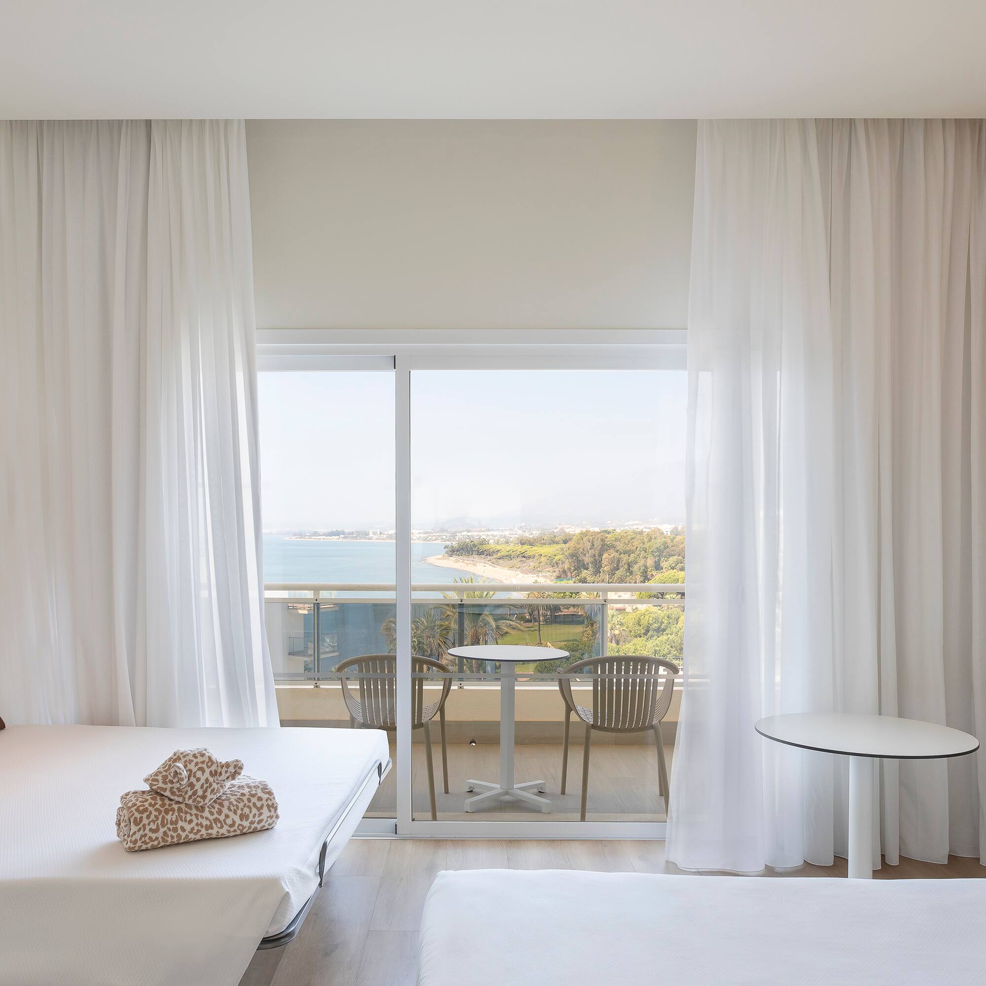 a room with a view of the ocean and a table and chairs