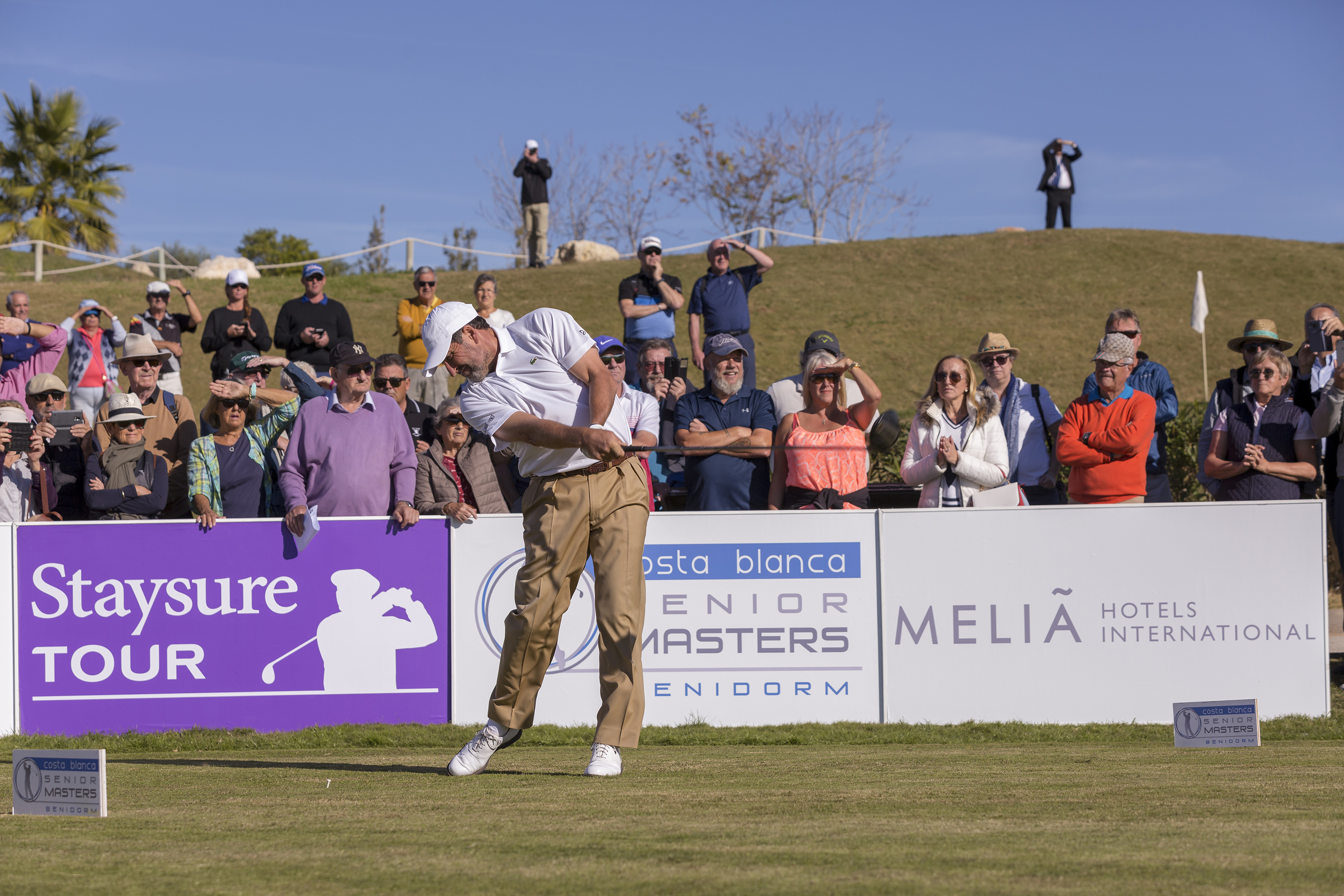 Golfer swinging on sunny golf course during Staysure Tour Senior Masters.