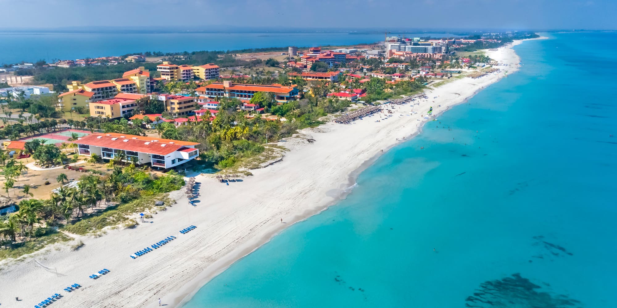 a beach with buildings and blue water