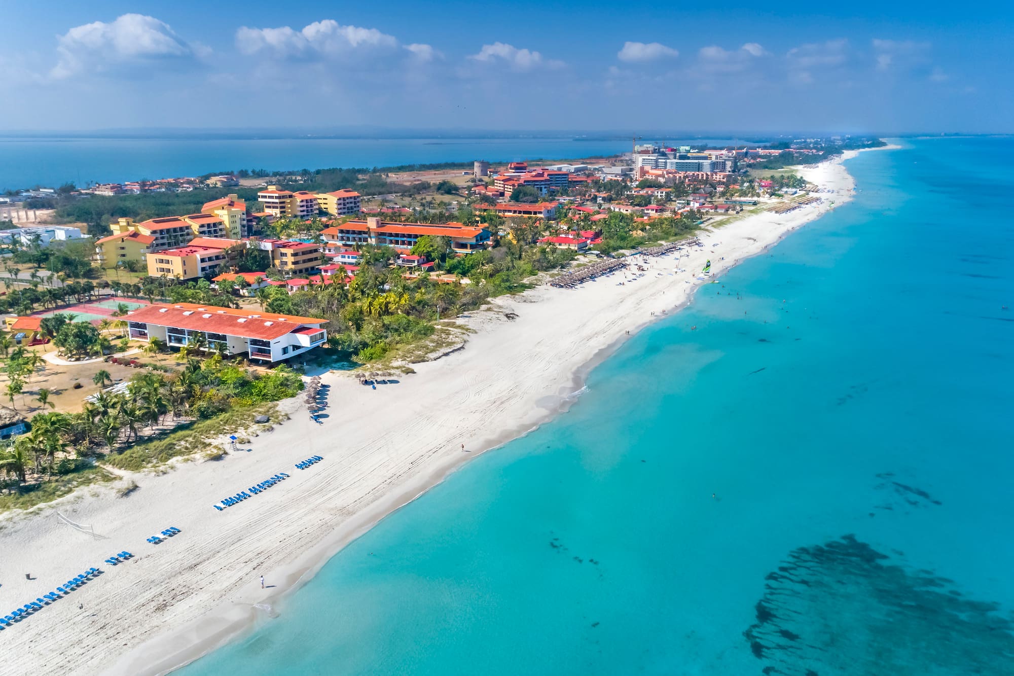 a beach with buildings and blue water