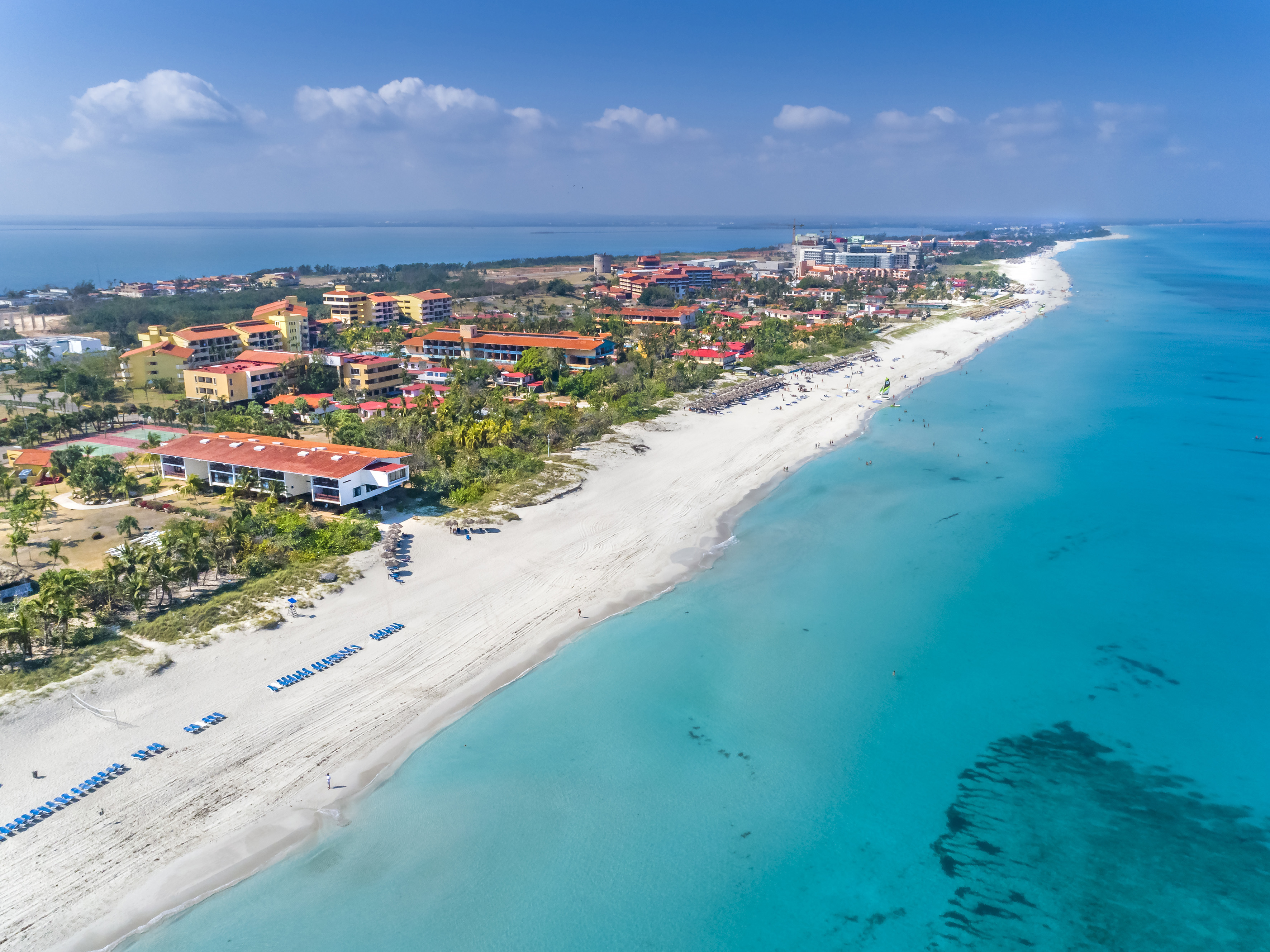 a beach with buildings and blue water