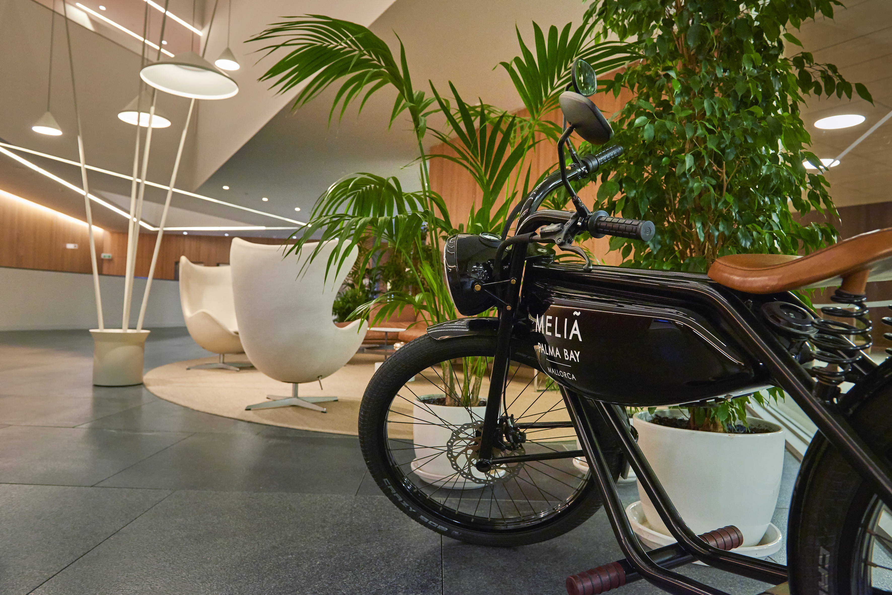 Black Meliá Palma Bay e-bike in modern hotel lobby lounge with plants.