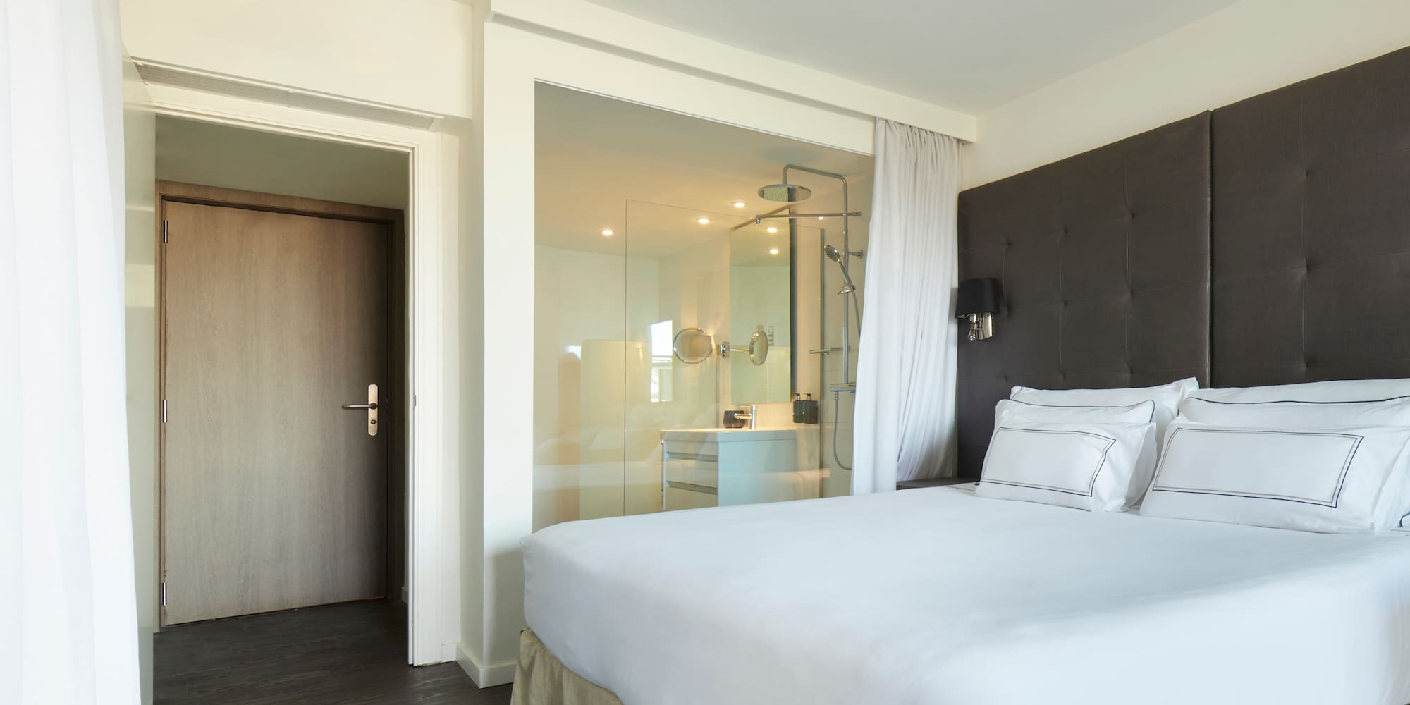 a bed with white sheets and a glass door