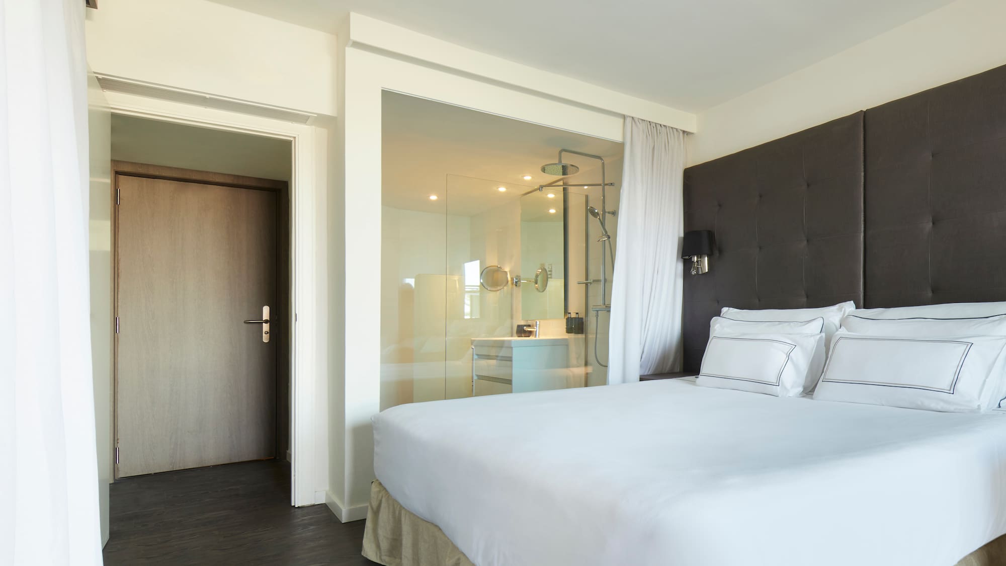 a bed with white sheets and a glass door