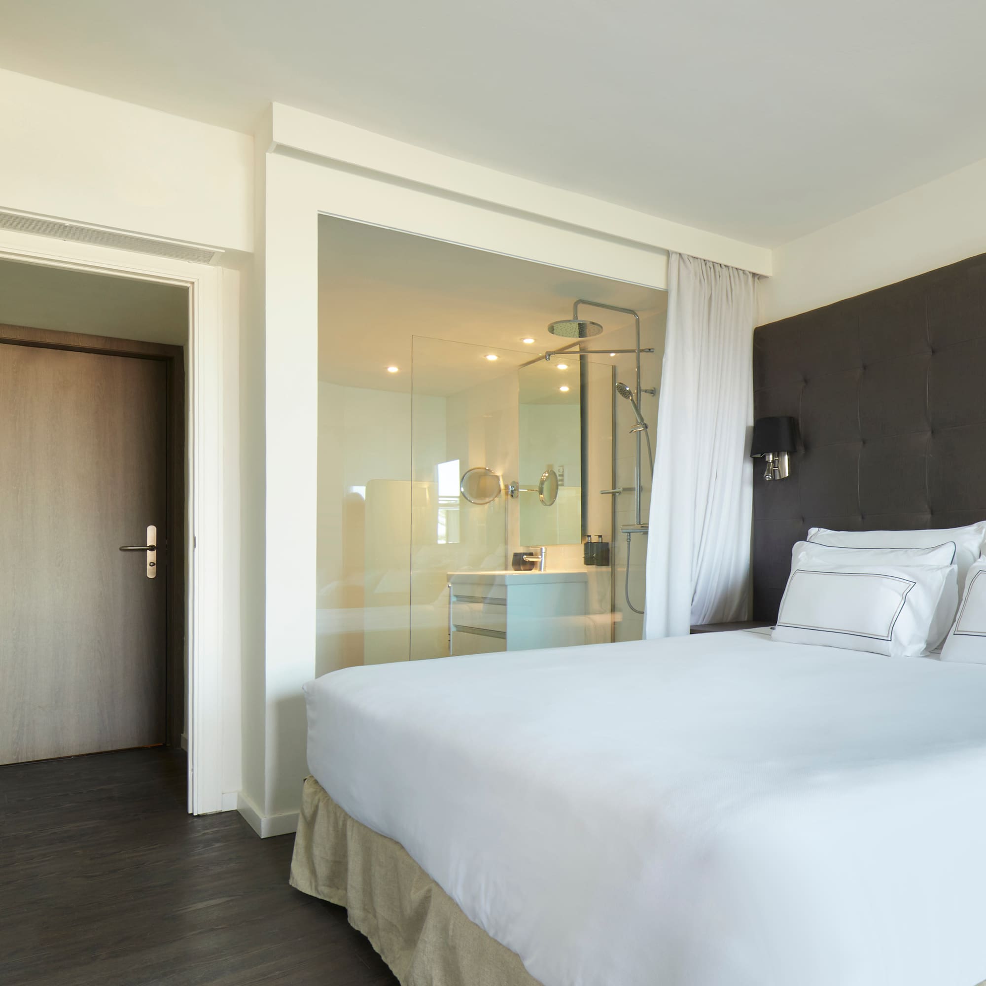 a bed with white sheets and a glass door