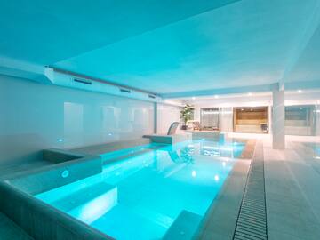 a indoor pool with a deck and a chair