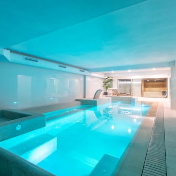 a indoor pool with a deck and a chair