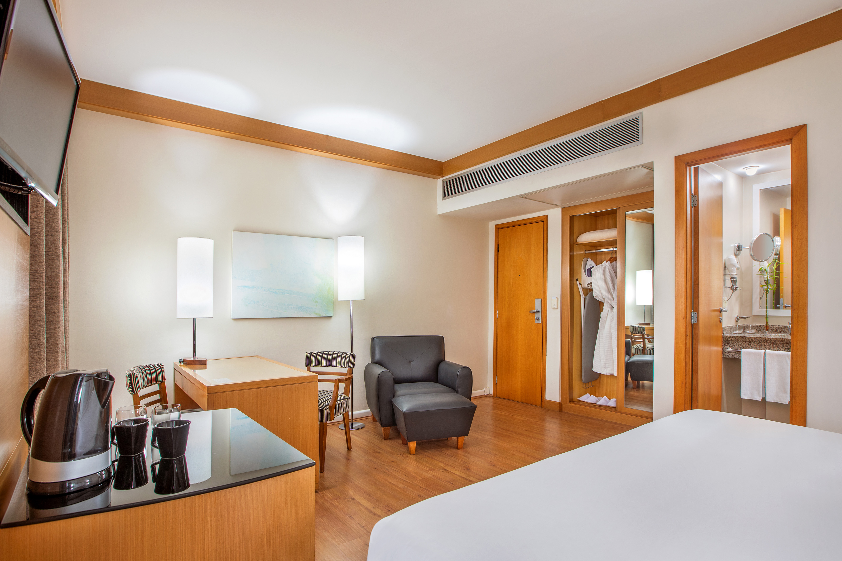 Modern hotel guest room with work desk, armchair, and private bathroom.