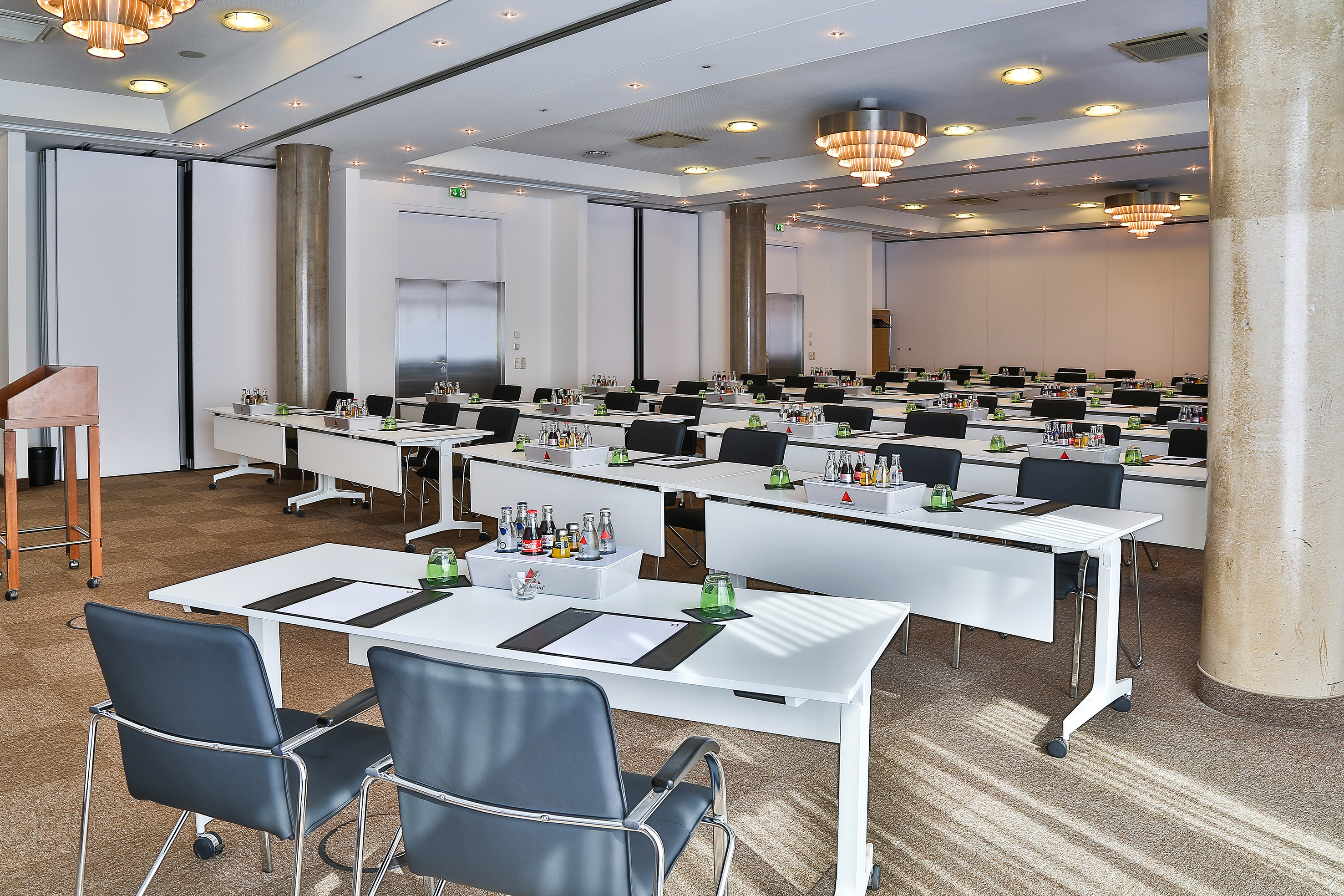 Modern conference room with tables, chairs, and refreshments, ready for a meeting.