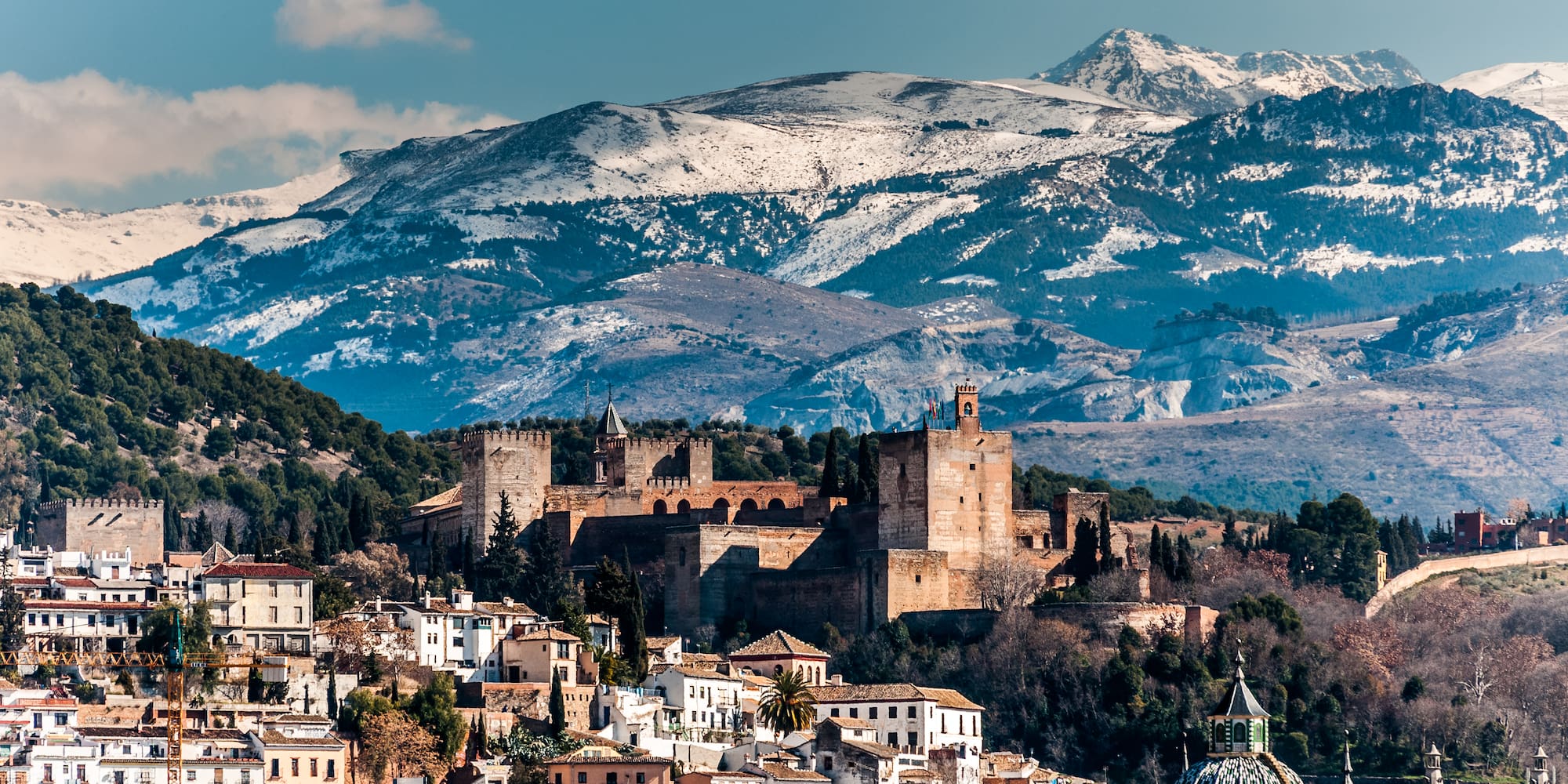 a city with a castle and mountains in the background