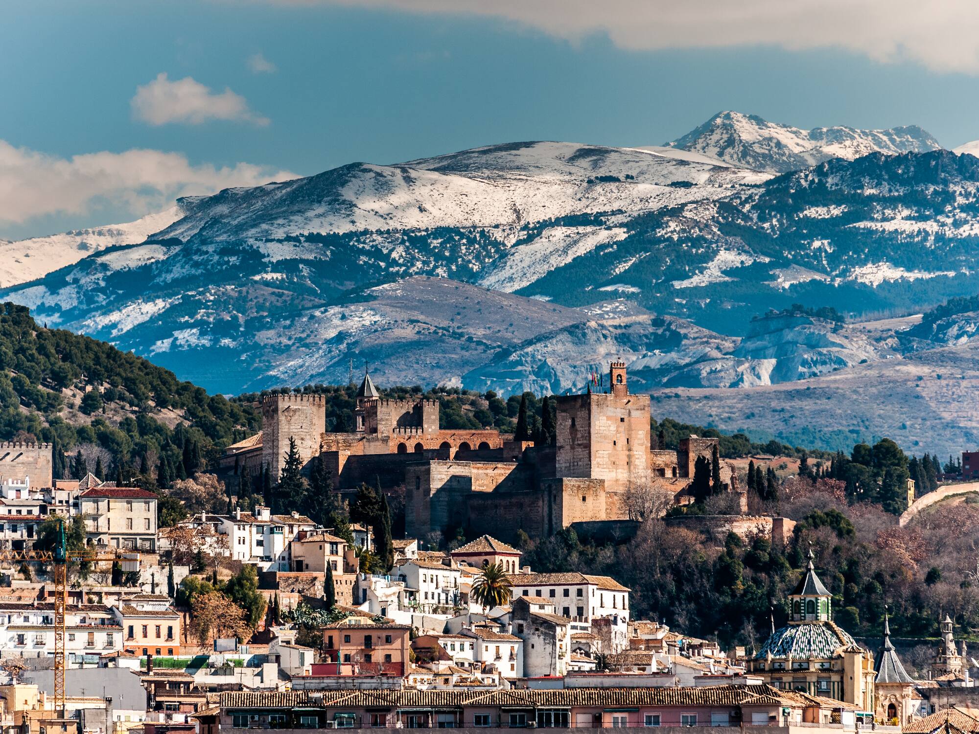 a city with a castle and mountains in the background