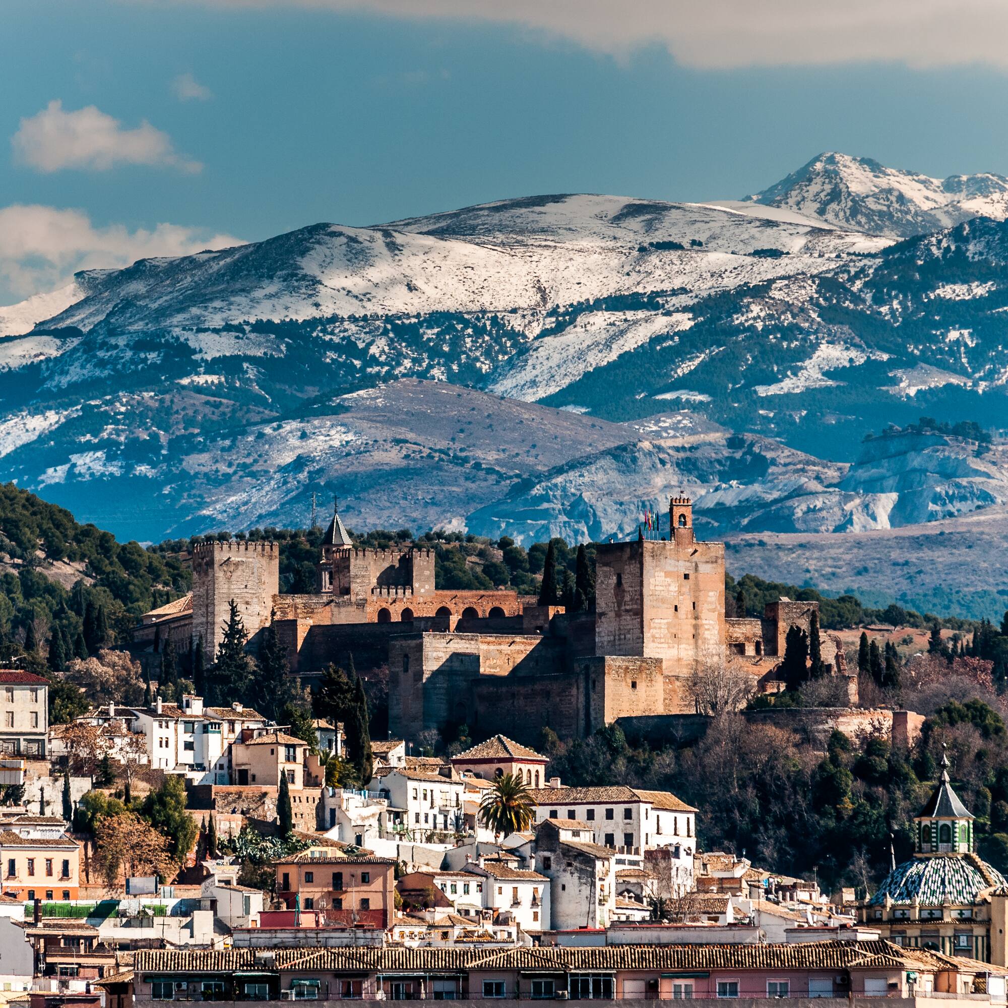 a city with a castle and mountains in the background