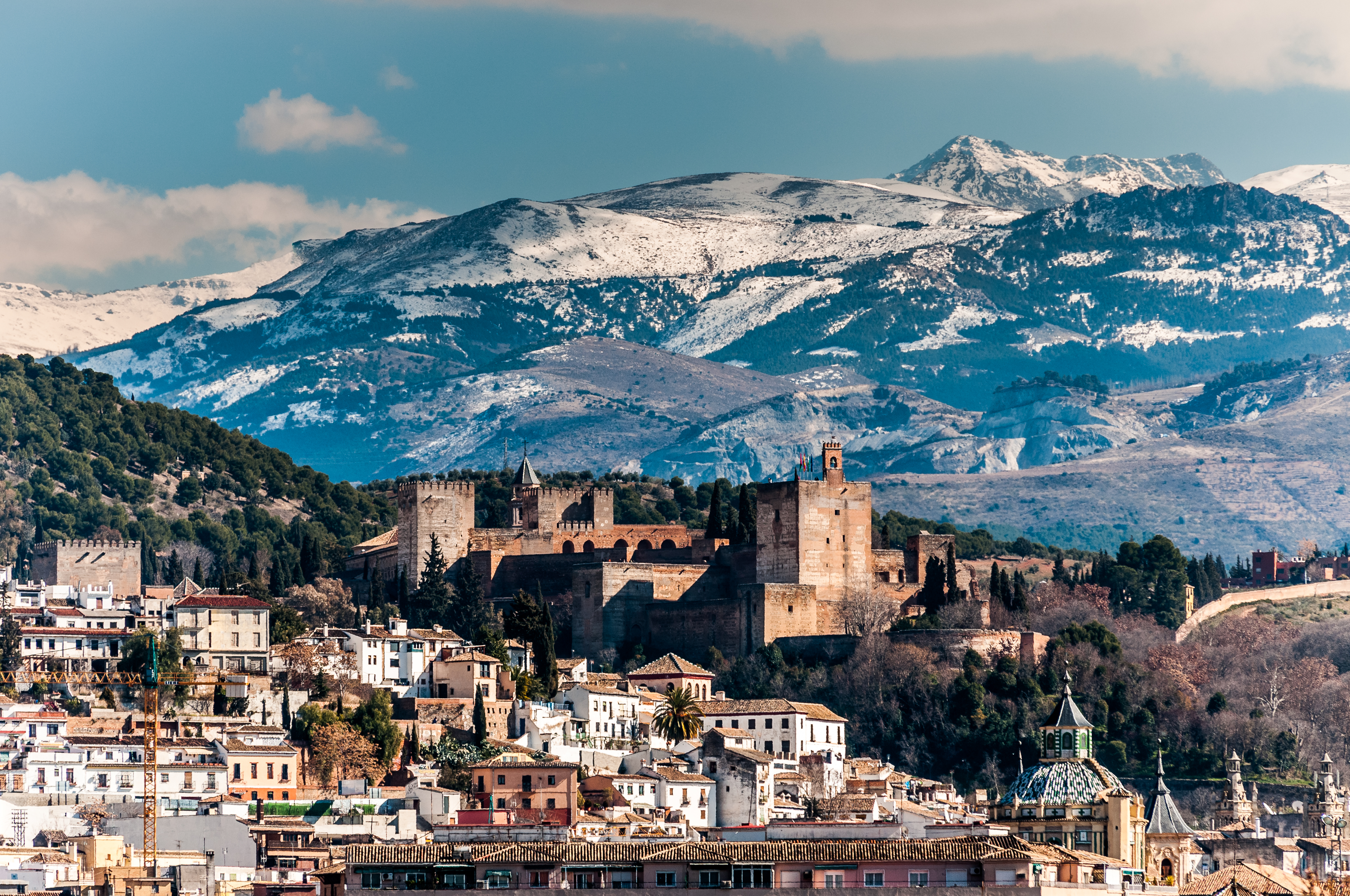 Alhambra palace and Granada city against snow-capped Sierra Nevada mountains.