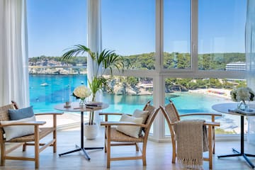 a room with a view of the ocean and a table and chairs