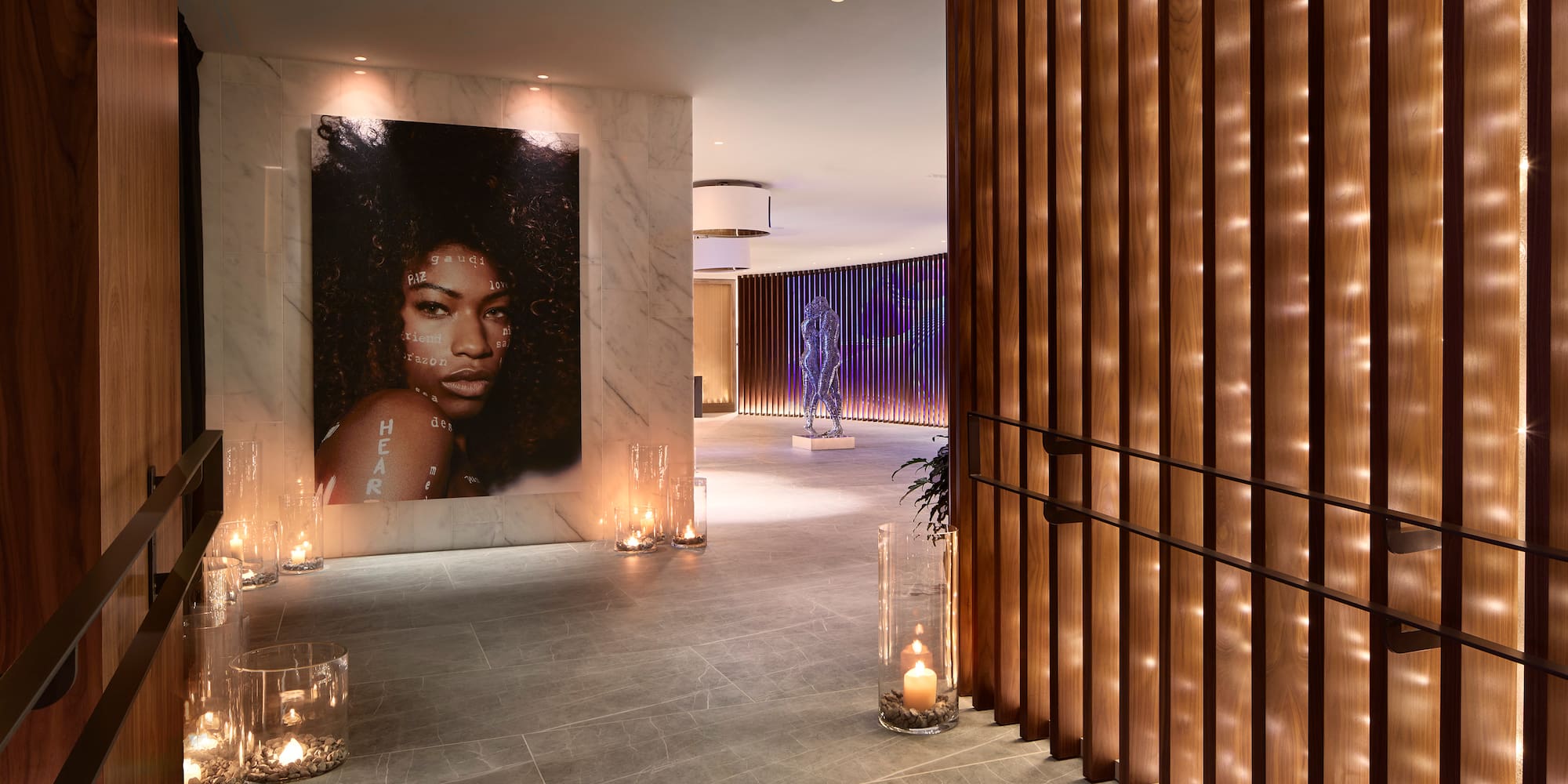 a large poster of a woman on a wall with candles