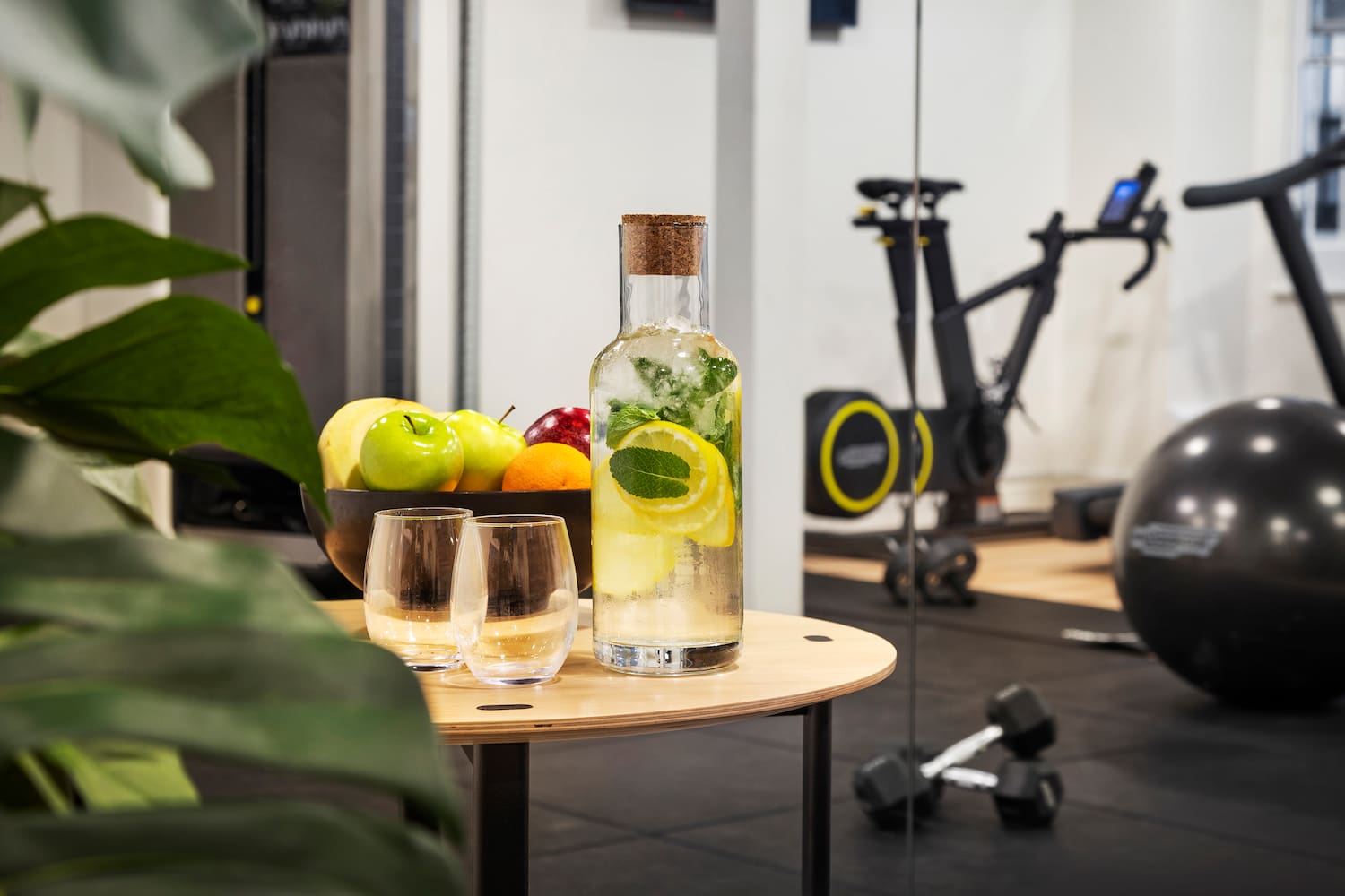 a bottle of water with fruit and glasses on a table