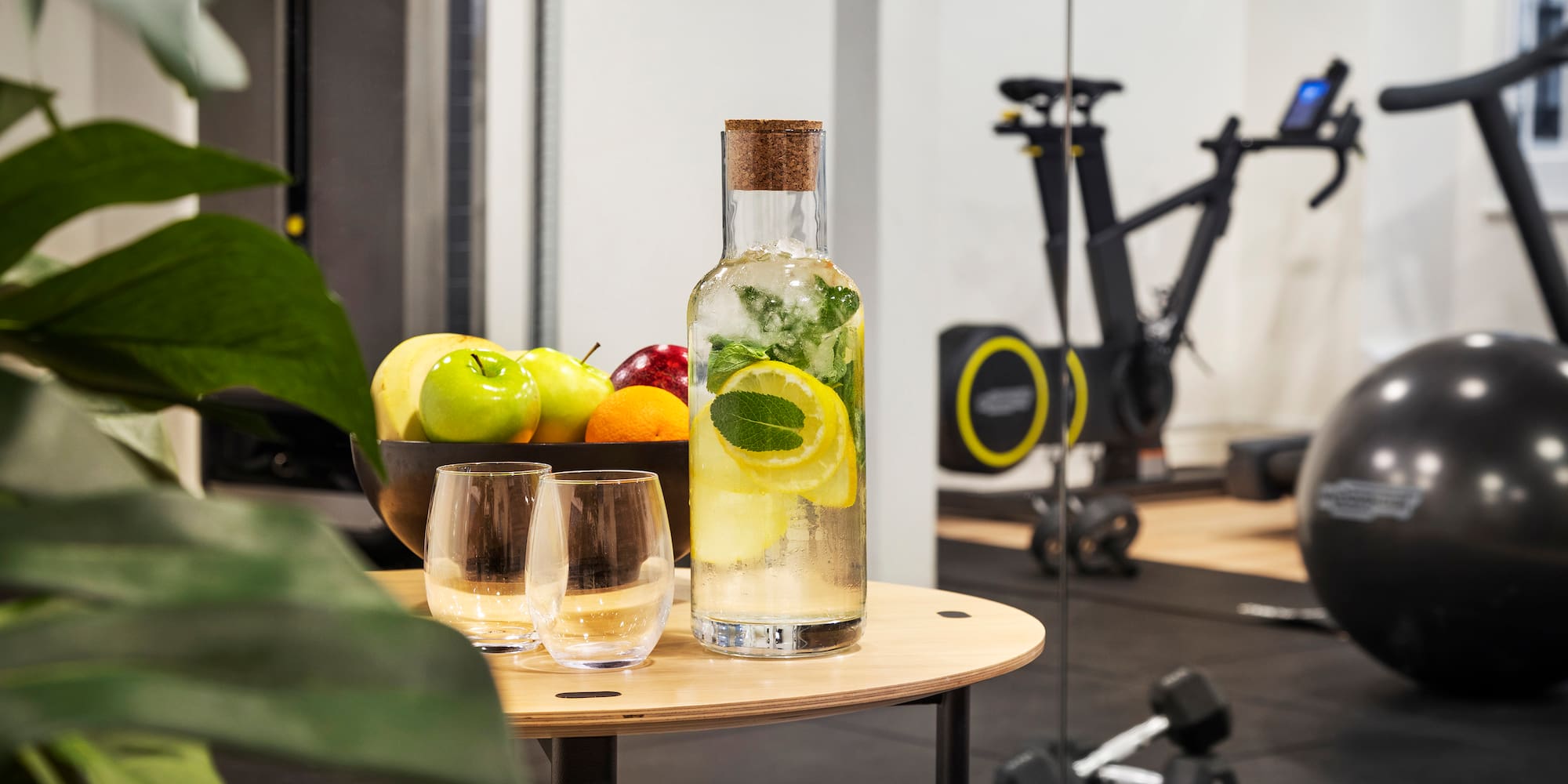 a bottle of water with fruit and glasses on a table