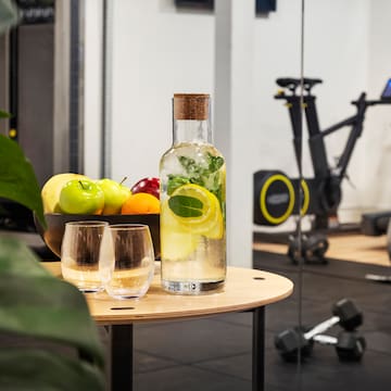 a bottle of water with fruit and glasses on a table