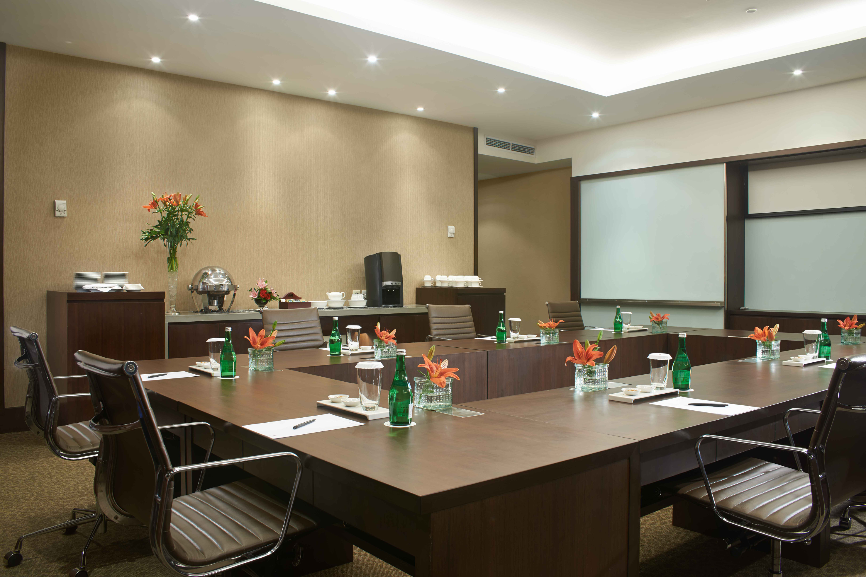 Elegant conference room with U-shaped table, leather chairs, and service area.