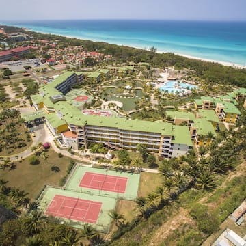 an aerial view of a resort with a swimming pool and tennis courts