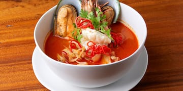 a bowl of soup with seafood and herbs