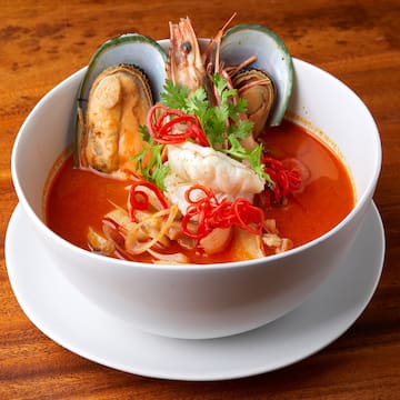 a bowl of soup with seafood and herbs