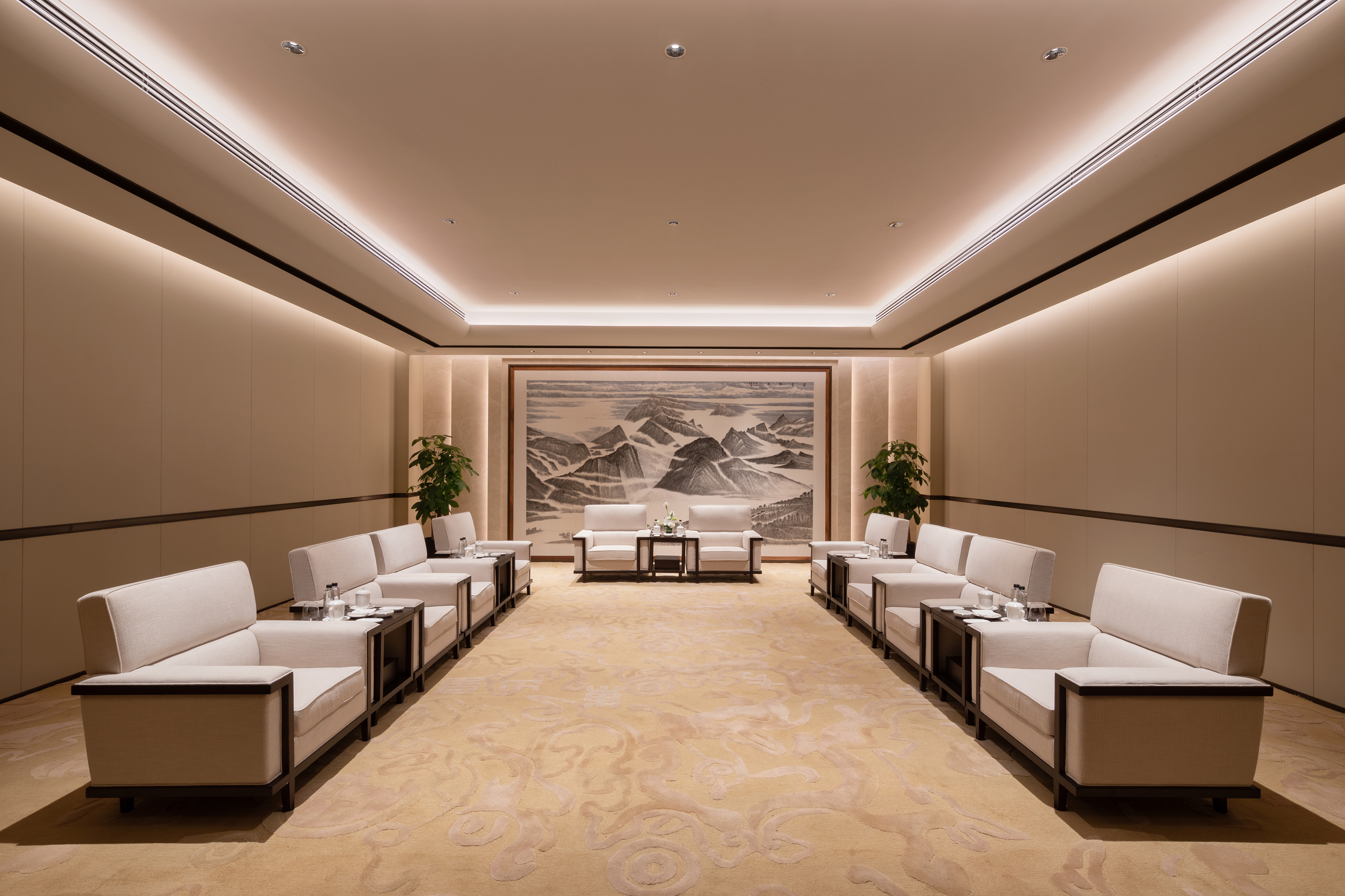 Symmetric luxury lounge with beige armchairs, warm lighting, and mountain artwork.