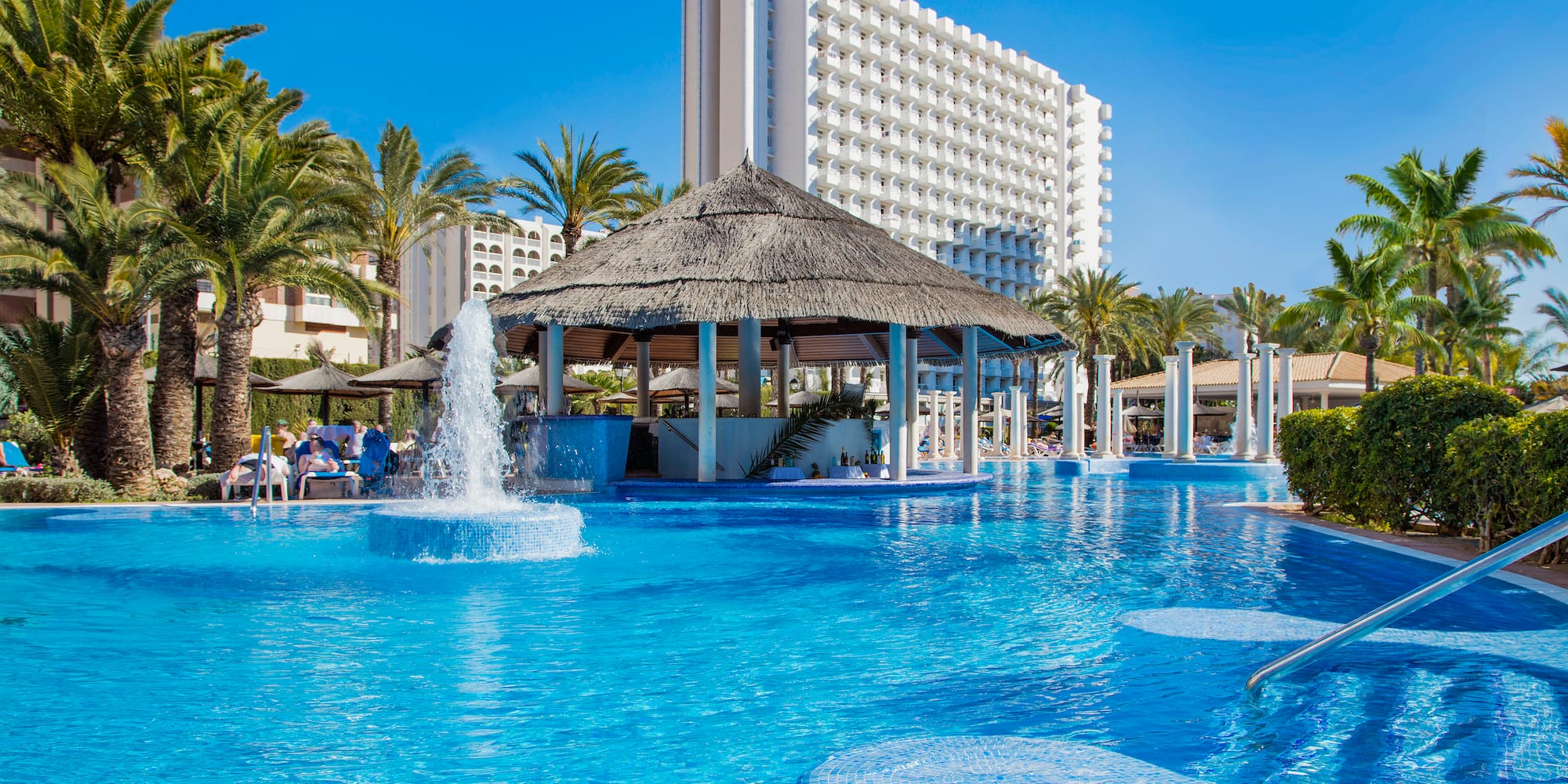 a pool with water fountain and a thatched roof