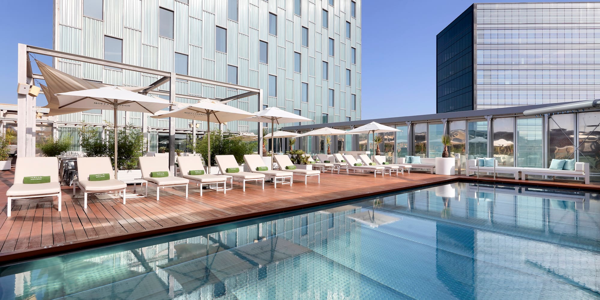a pool with chairs and umbrellas in front of a building
