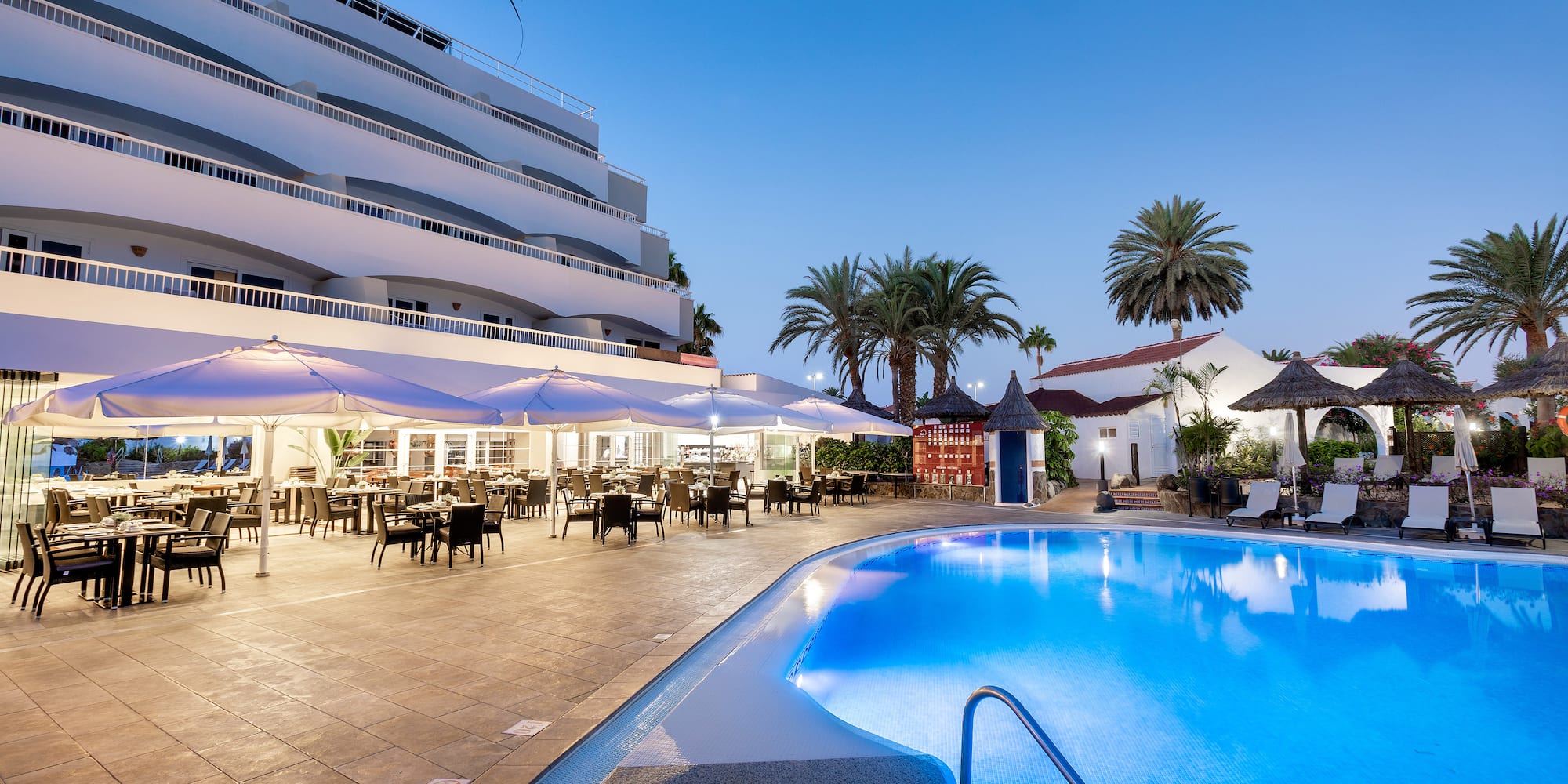 a pool with tables and chairs in front of a building