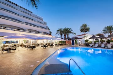 a pool with tables and chairs in front of a building