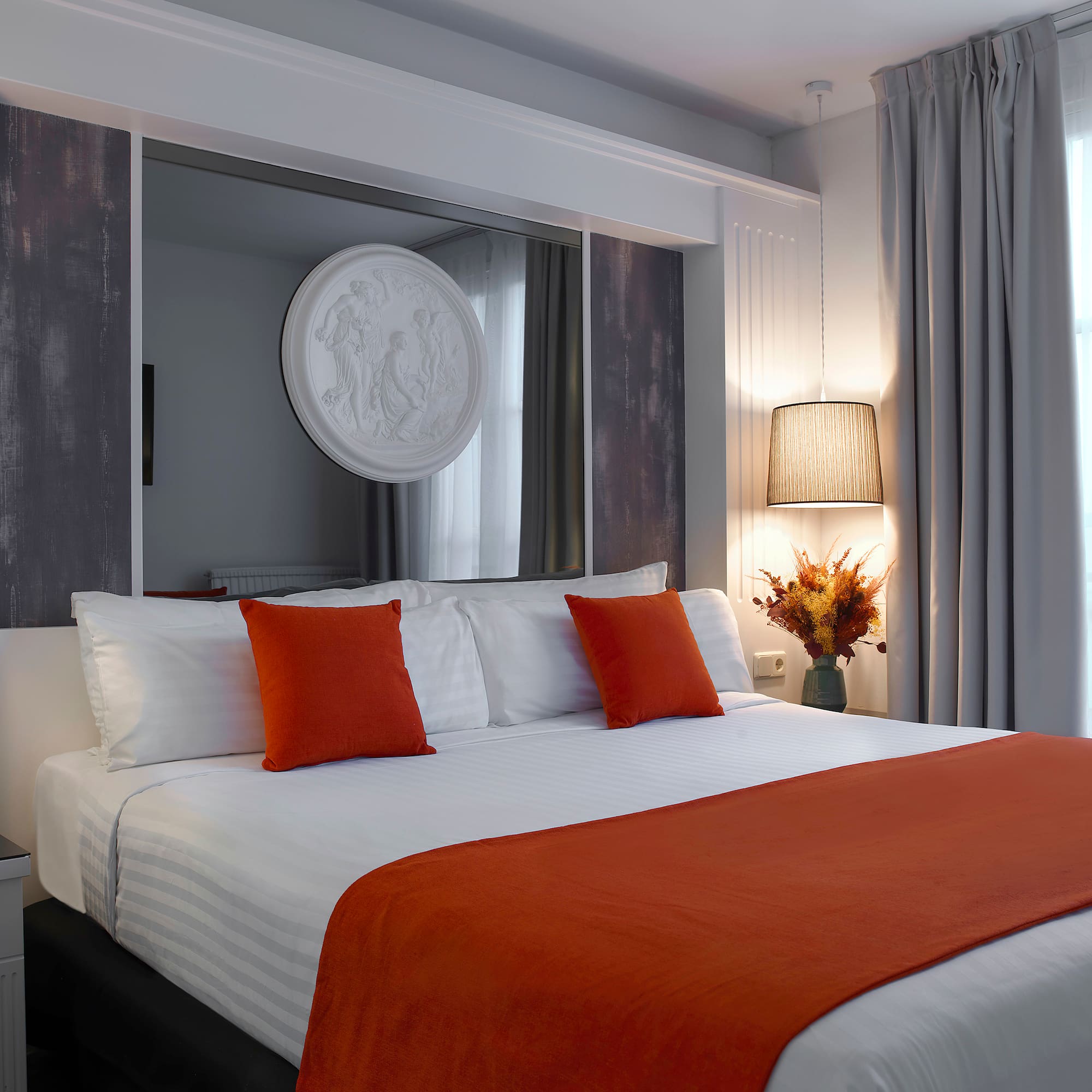 a bed with orange pillows and a mirror above it