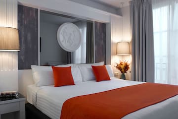 a bed with orange pillows and a mirror above it