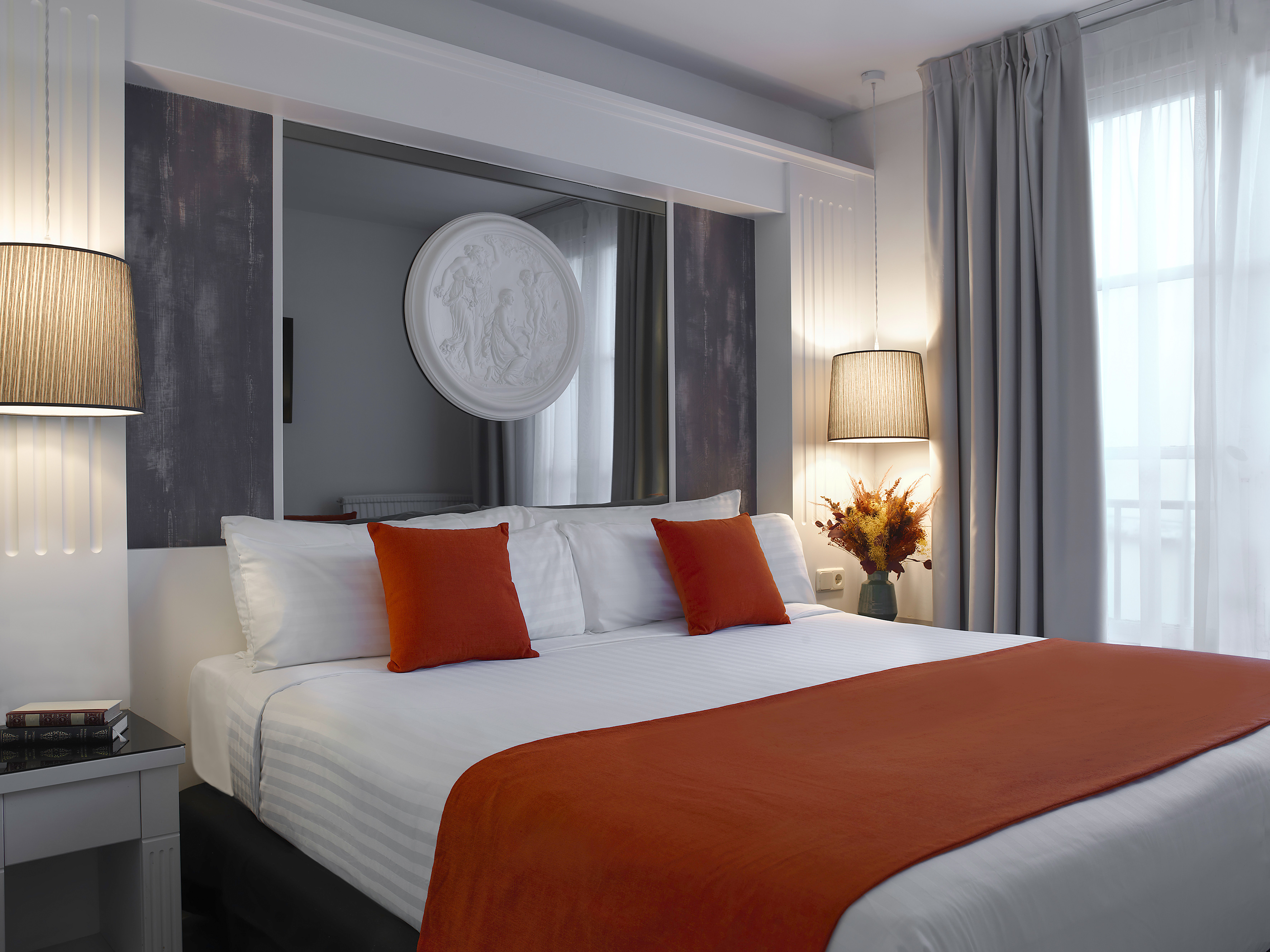 a bed with orange pillows and a mirror above it